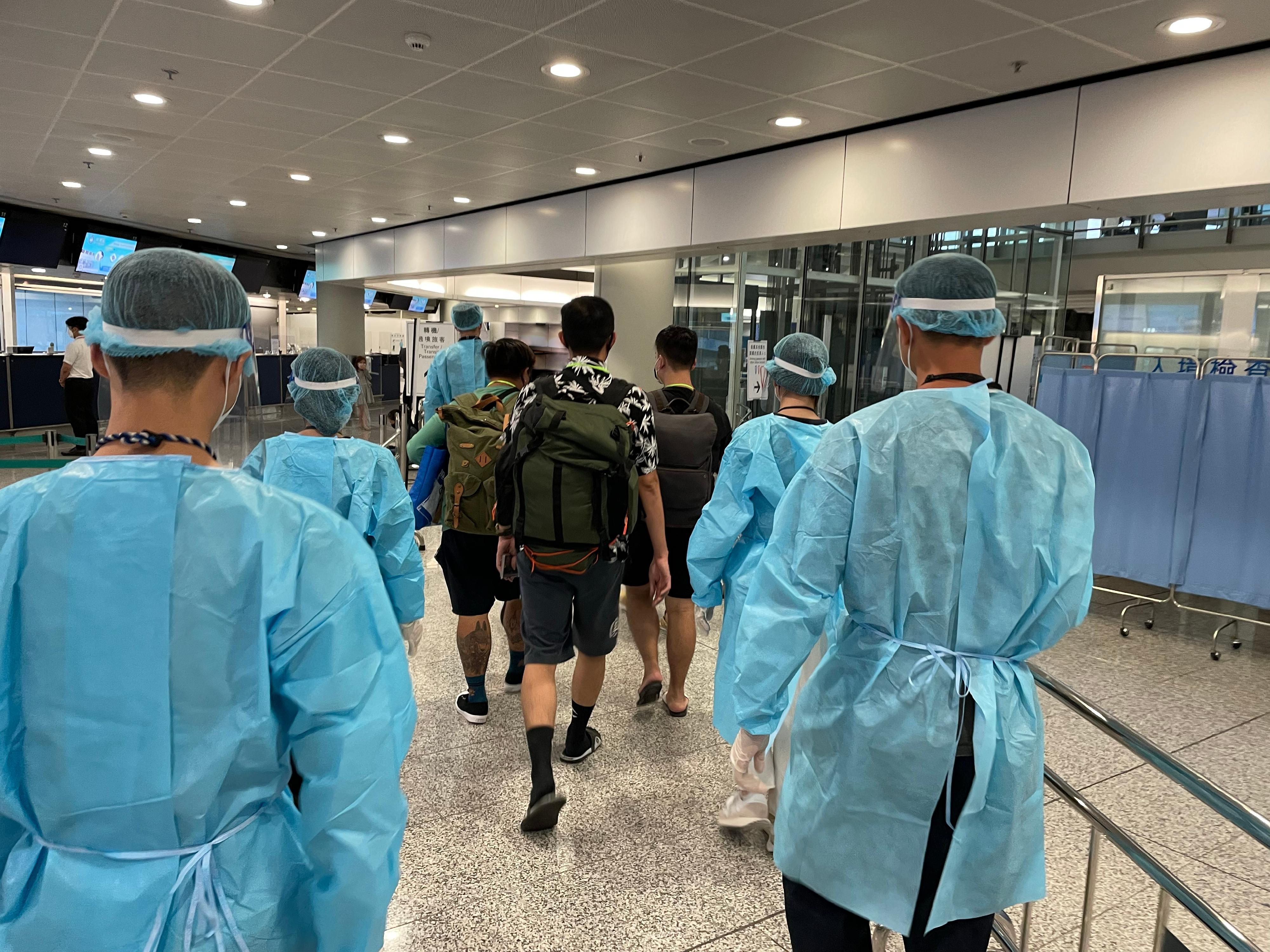 今日（八月二十六日）再有求助港人安全抵達香港國際機場。圖示穿上防護裝備的入境處人員，協助有關求助港人前往專用入境櫃檯辦理出入境手續。