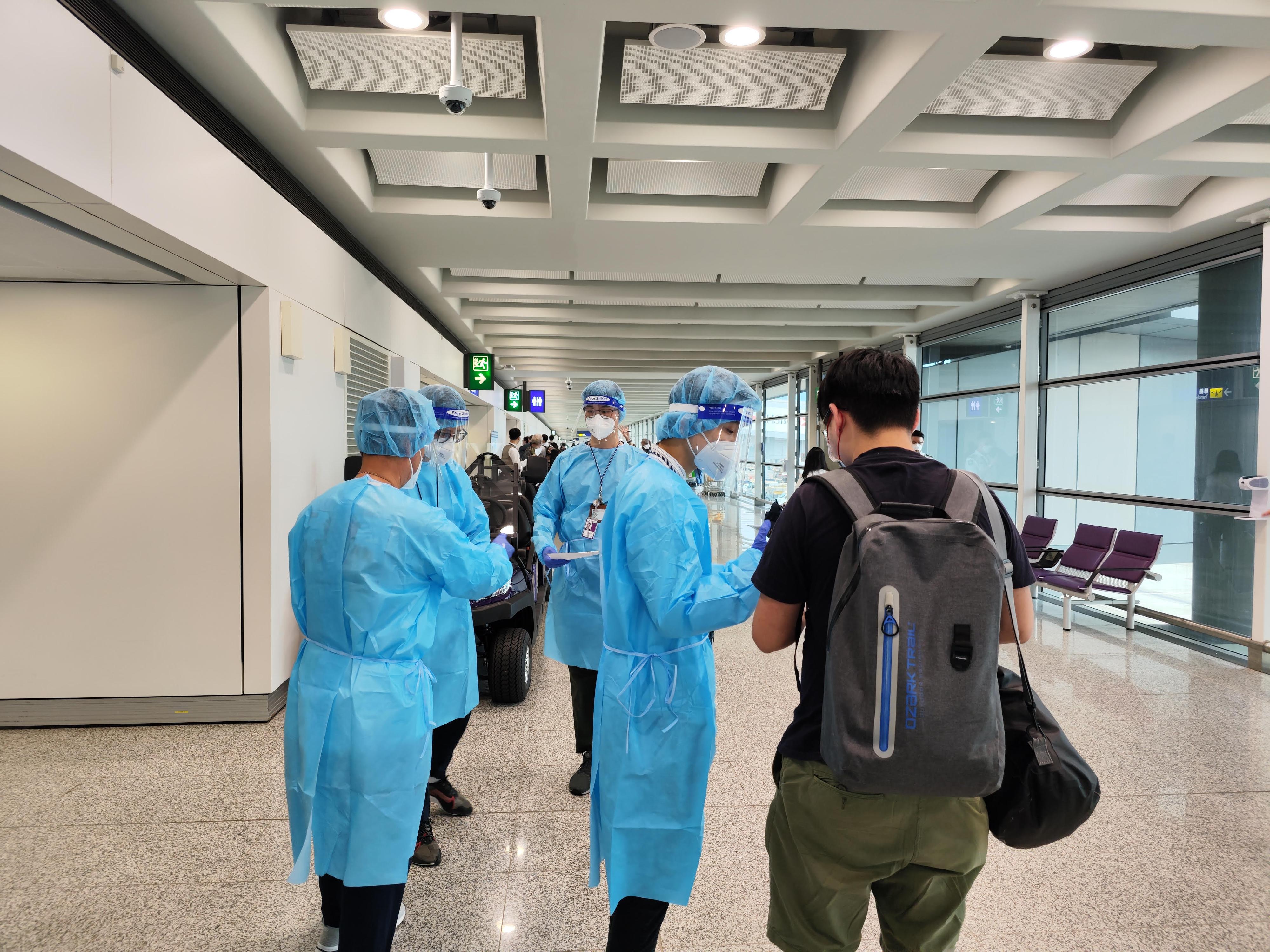 一名求助港人今日（八月二十八日）安全抵達香港國際機場。圖示穿上防護裝備的入境事務處人員，協助有關求助港人前往專用入境櫃檯辦理出入境手續。