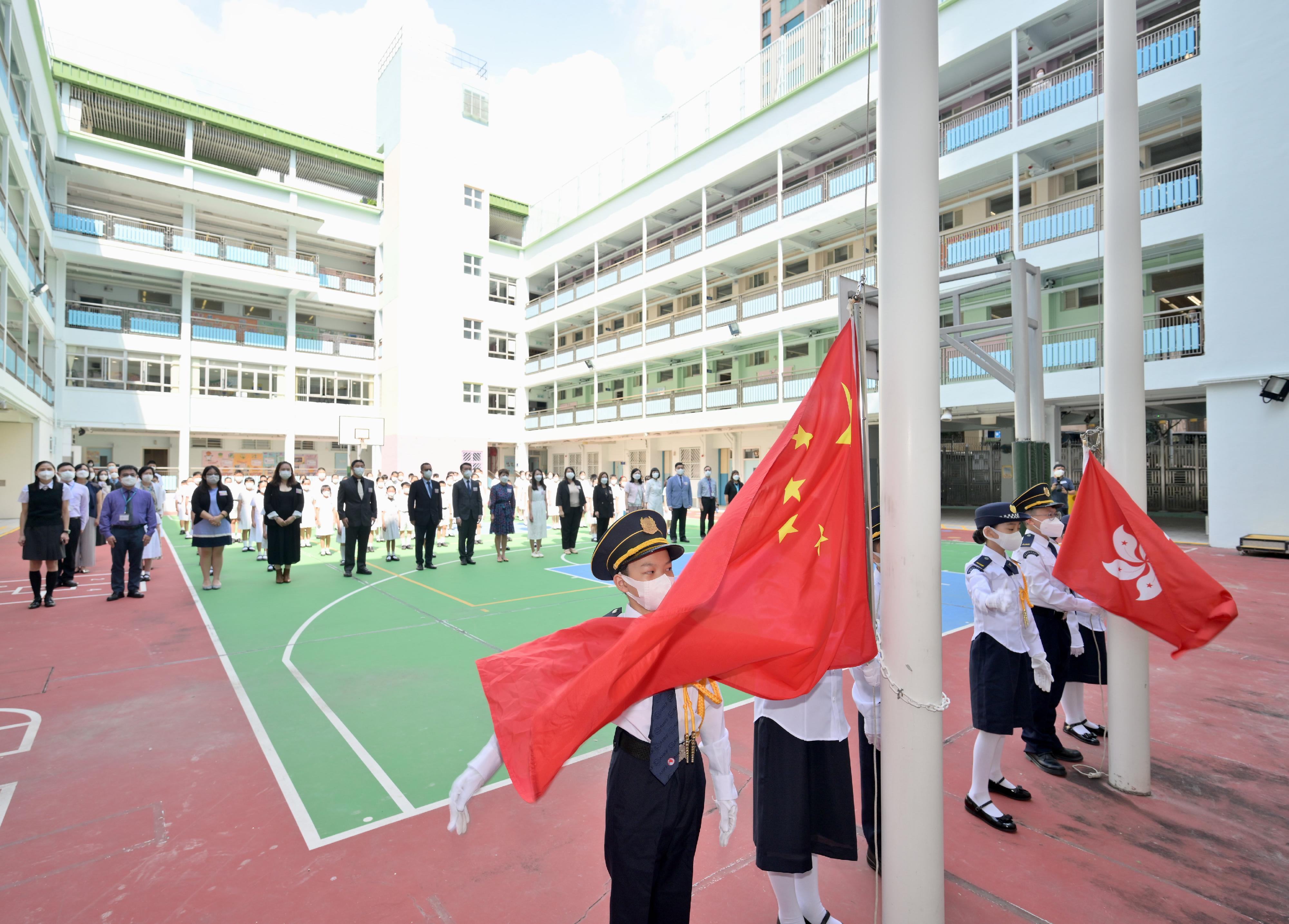 教育局副局長施俊輝於今日（九月一日）開學日探訪農圃道官立小學。圖示施俊輝（後排左七）在開學禮與學生觀看升掛國旗。