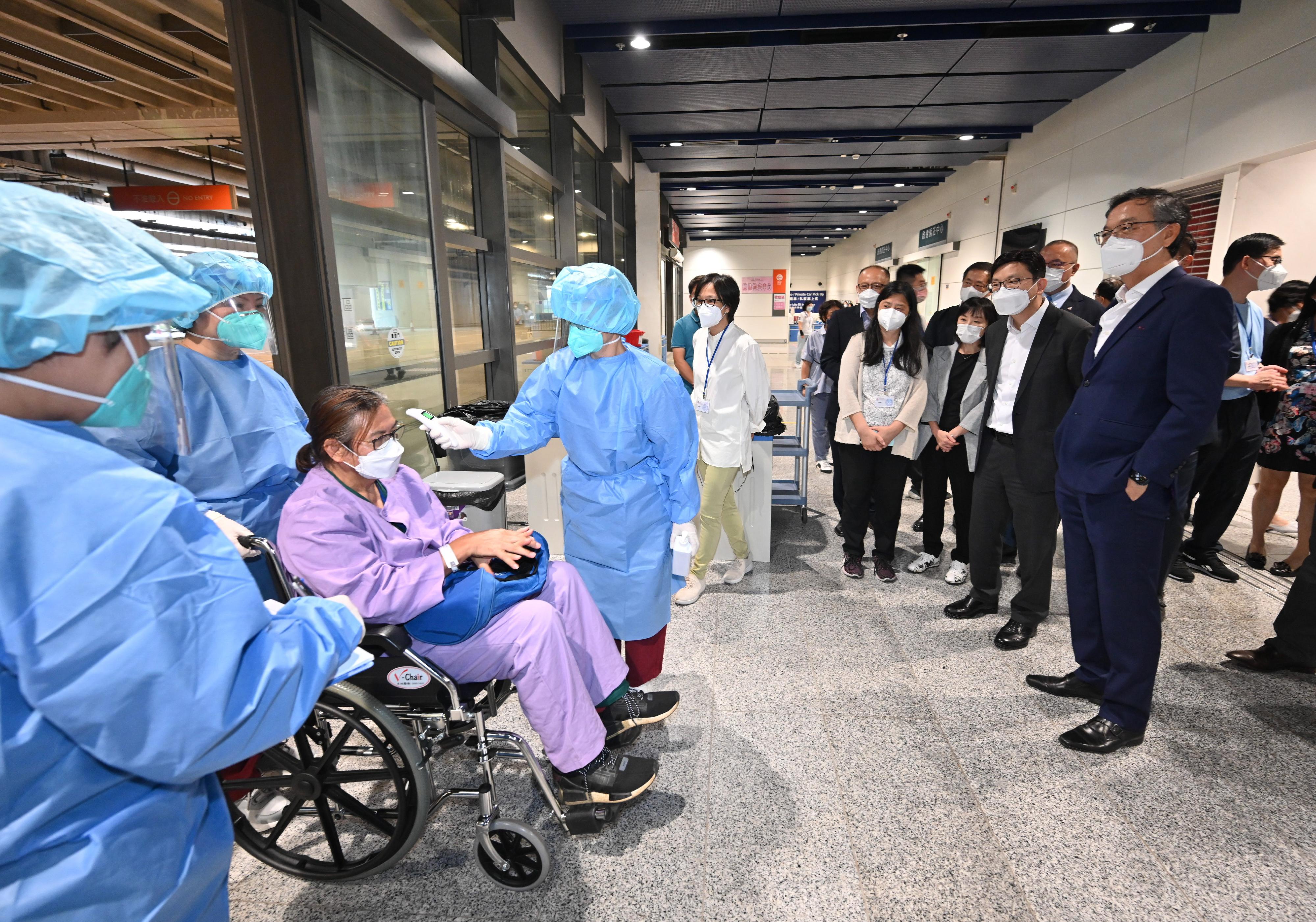 The Secretary for Labour and Welfare, Mr Chris Sun, today (September 1) visited the Kai Tak Quarantine Centre at the Kai Tak Cruise Terminal to learn more about the preparatory work prior to its commencement of operation tomorrow (September 2). Photo shows Mr Sun (front row, second right), accompanied by the Director of Social Welfare, Miss Charmaine Lee (front row, third right), and the Chief Executive Officer of Haven of Hope Christian Service, Dr Lam Ching-choi (front row, first right), watching a demonstration by staff of the care team on admission procedures for a resident of a residential care home for the elderly, including taking her body temperature first.