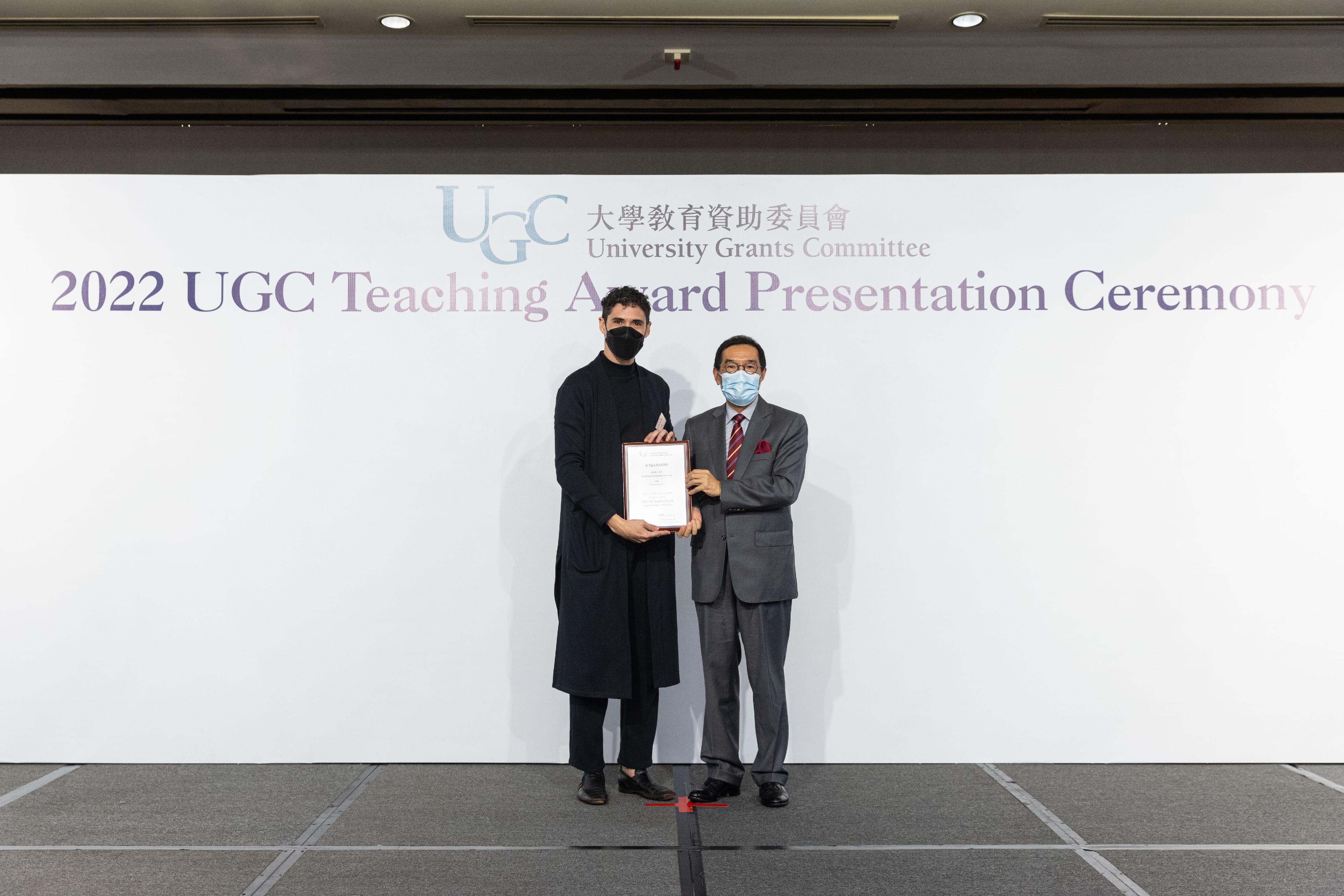 The Chairman of the University Grants Committee (UGC), Mr Carlson Tong (right), presents the 2022 UGC Teaching Award for Early Career Faculty Members to Dr Tulio Maximo.