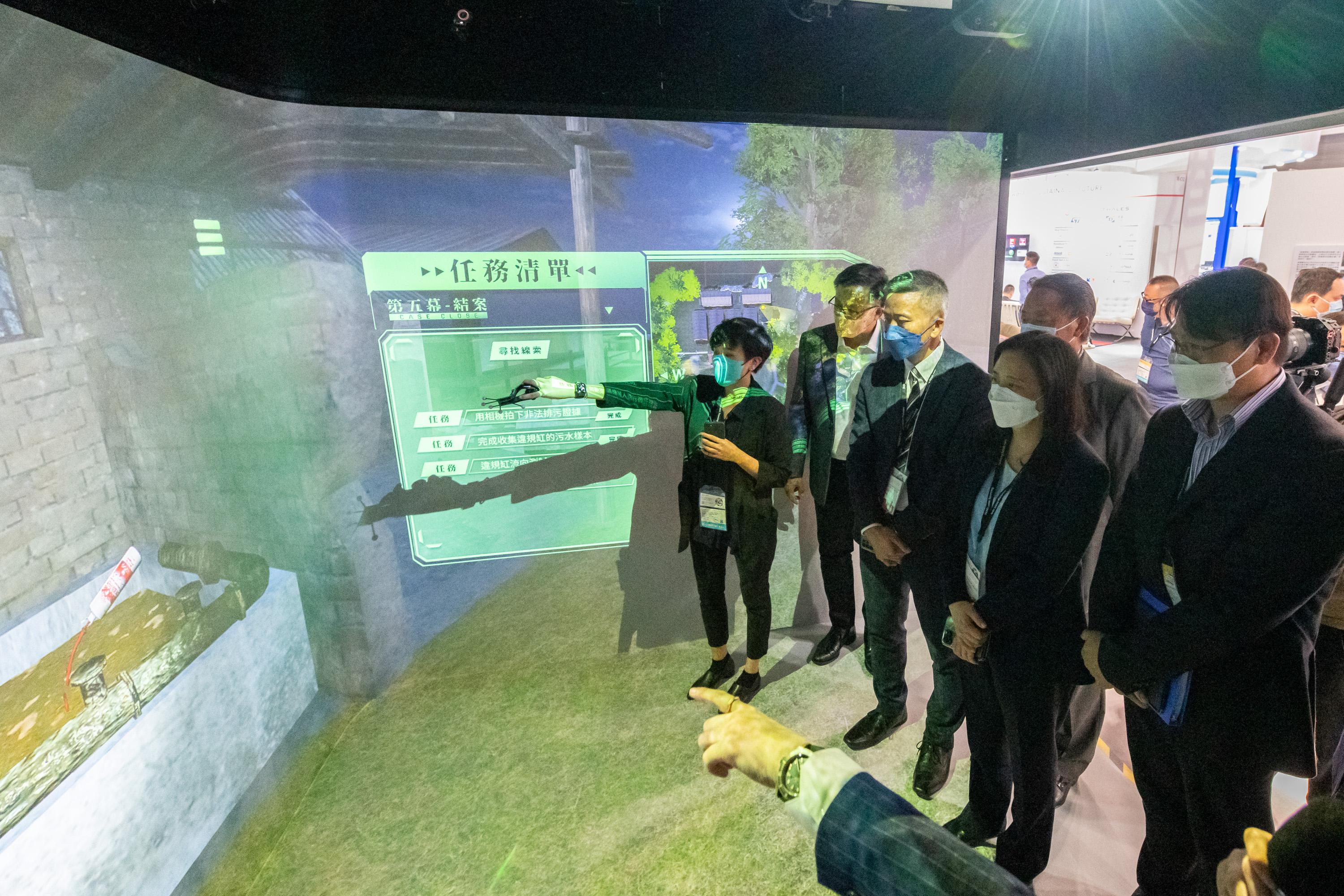 The Legislative Council (LegCo) Subcommittee on Matters Relating to the Development of Smart City visits the Smart Government Pavilion at the International ICT Expo 2022 today (October 13). Photo shows LegCo Members learning about the virtual reality enforcement training on illegal discharge from livestock farms through the interactive device at the Smart Government Pavilion.