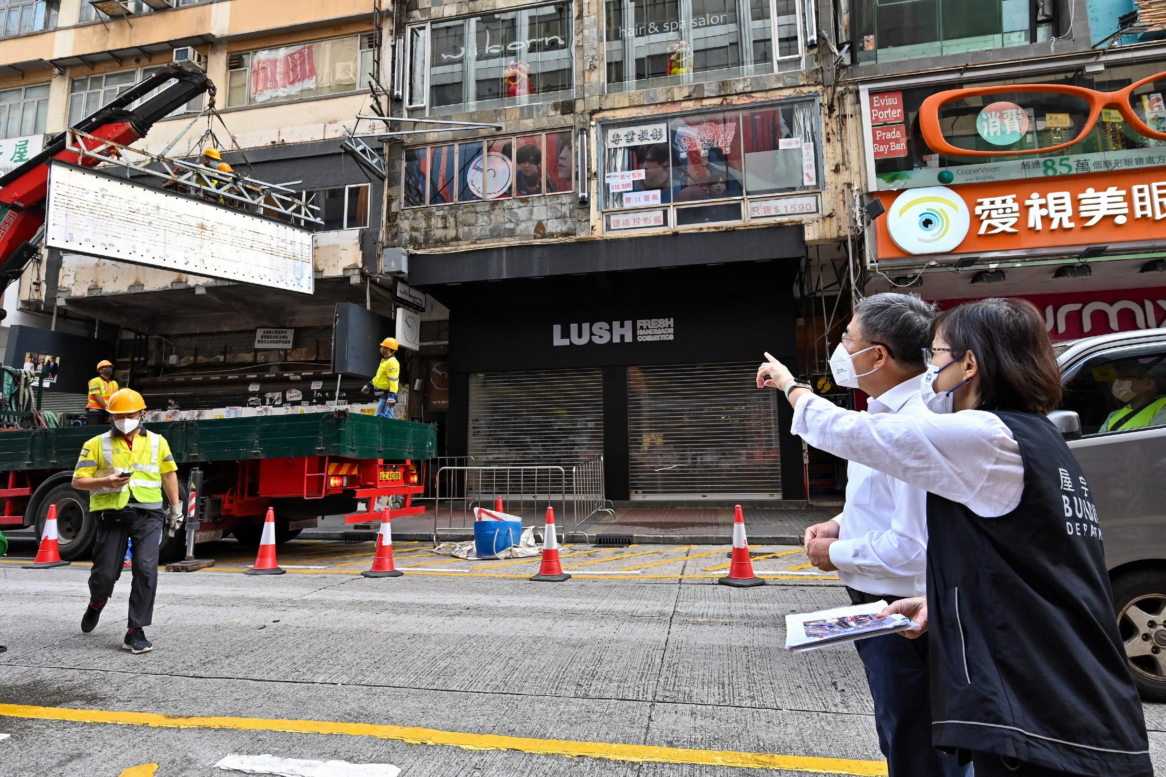 The Deputy Chief Secretary for Administration, Mr Cheuk Wing-hing (left), is given an on-site briefing by the Director of Buildings, Ms Clarice Yu (right), at Sai Yeung Choi Street South in Mong Kok this morning (November 15) on the work of the Buildings Department in removing dangerous and abandoned signboards.