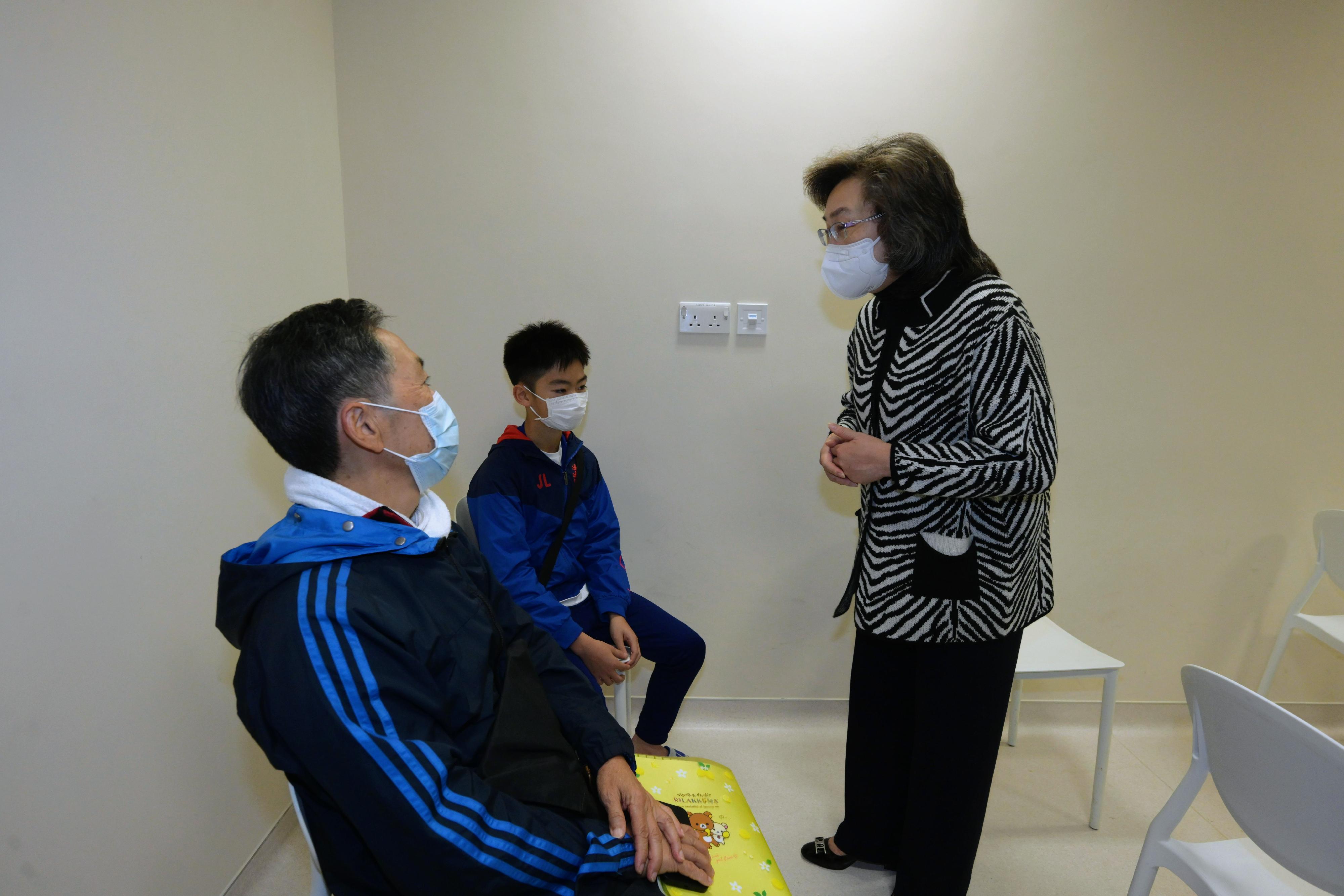 公務員事務局局長楊何蓓茵今日（十二月一日）到香港中文大學醫院社區疫苗接種中心，視察市民接種復必泰二價疫苗的情況。圖示楊何蓓茵（右一）與前來接種第二劑新冠疫苗的13歲男童及其祖父交談，了解他們對接種新冠疫苗的意見。