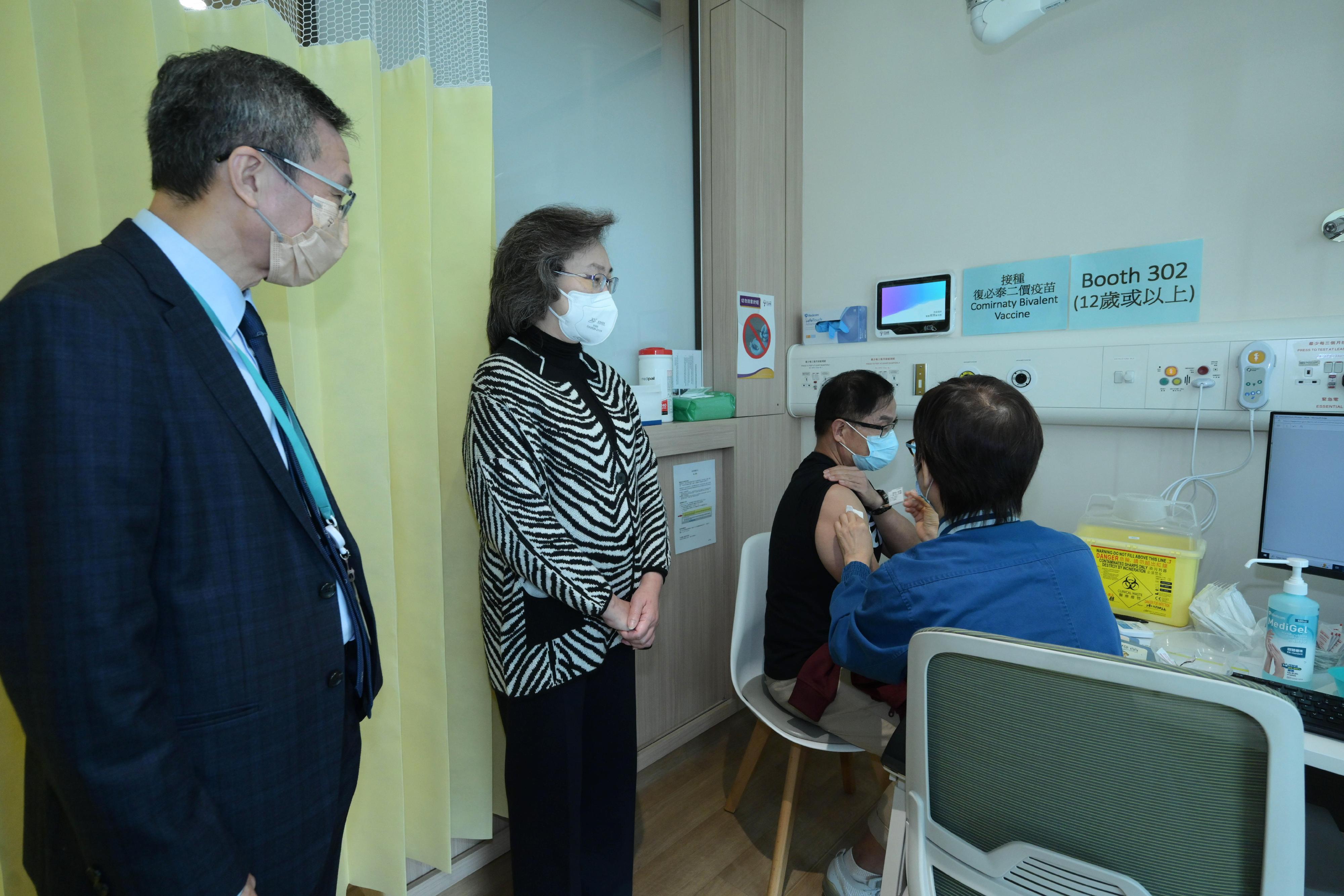 The Secretary for the Civil Service, Mrs Ingrid Yeung, visited the Community Vaccination Centre at CUHK Medical Centre today (December 1) to see for herself the BioNTech bivalent vaccination of the public and learn about the views of the vaccine recipients. Photo shows a 68-year-old man (second right) receiving the BioNTech bivalent vaccine. He also received the seasonal influenza vaccine at the same time today. Looking on are Mrs Yeung (second left) and the Chief Executive Officer of the CUHK Medical Centre, Dr Fung Hong (first left).