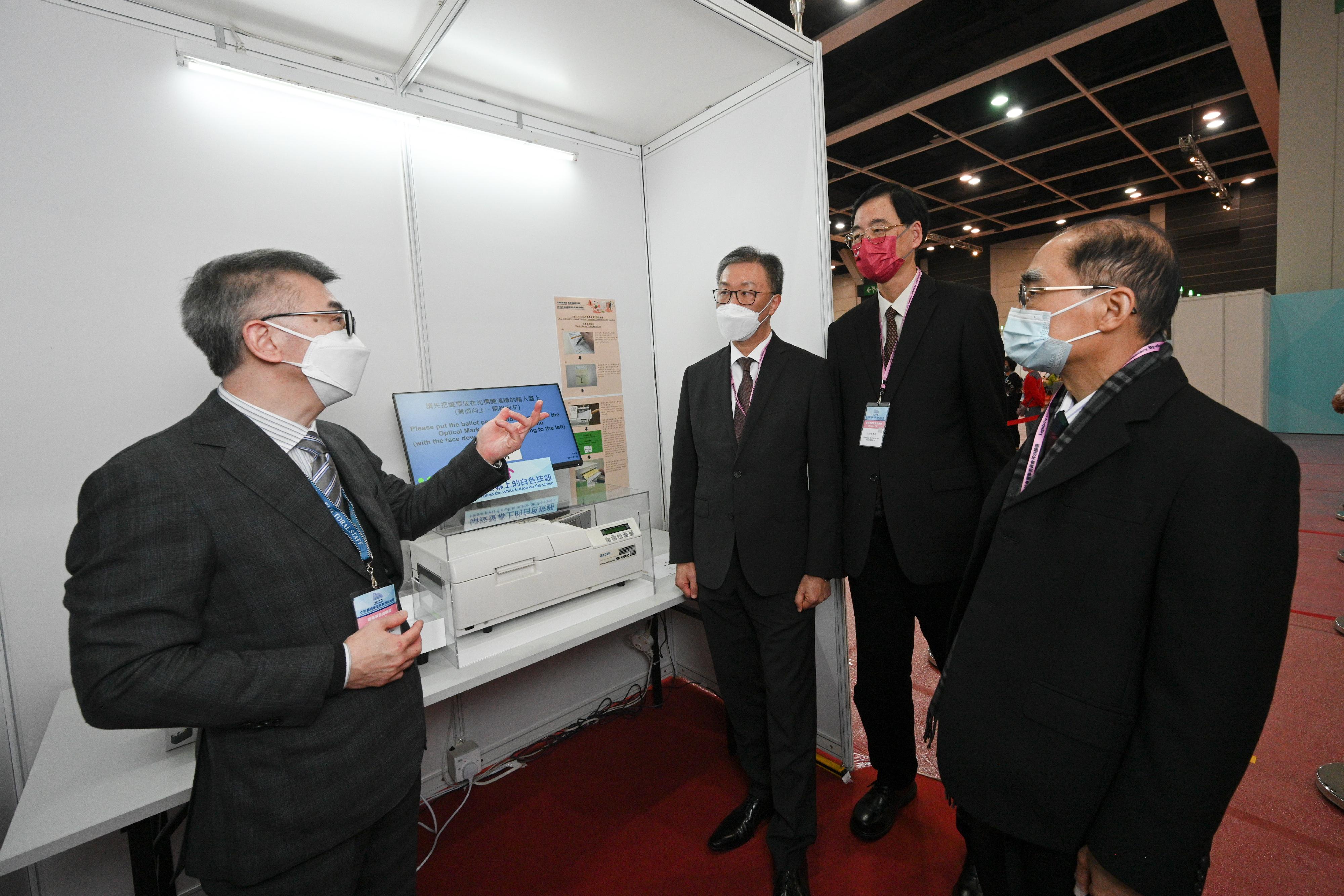 The Chairman of the Electoral Affairs Commission (EAC), Mr Justice David Lok (second left), EAC members Mr Arthur Luk, SC (first right), and Professor Daniel Shek (second right) were briefed by the Chief Electoral Officer of the Registration and Electoral Office, Mr Raymond Wang (first left), on the checking machines during their visit to the polling station of the 2022 Legislative Council Election Committee constituency by-election at the Hong Kong Convention and Exhibition Centre today (December 16).