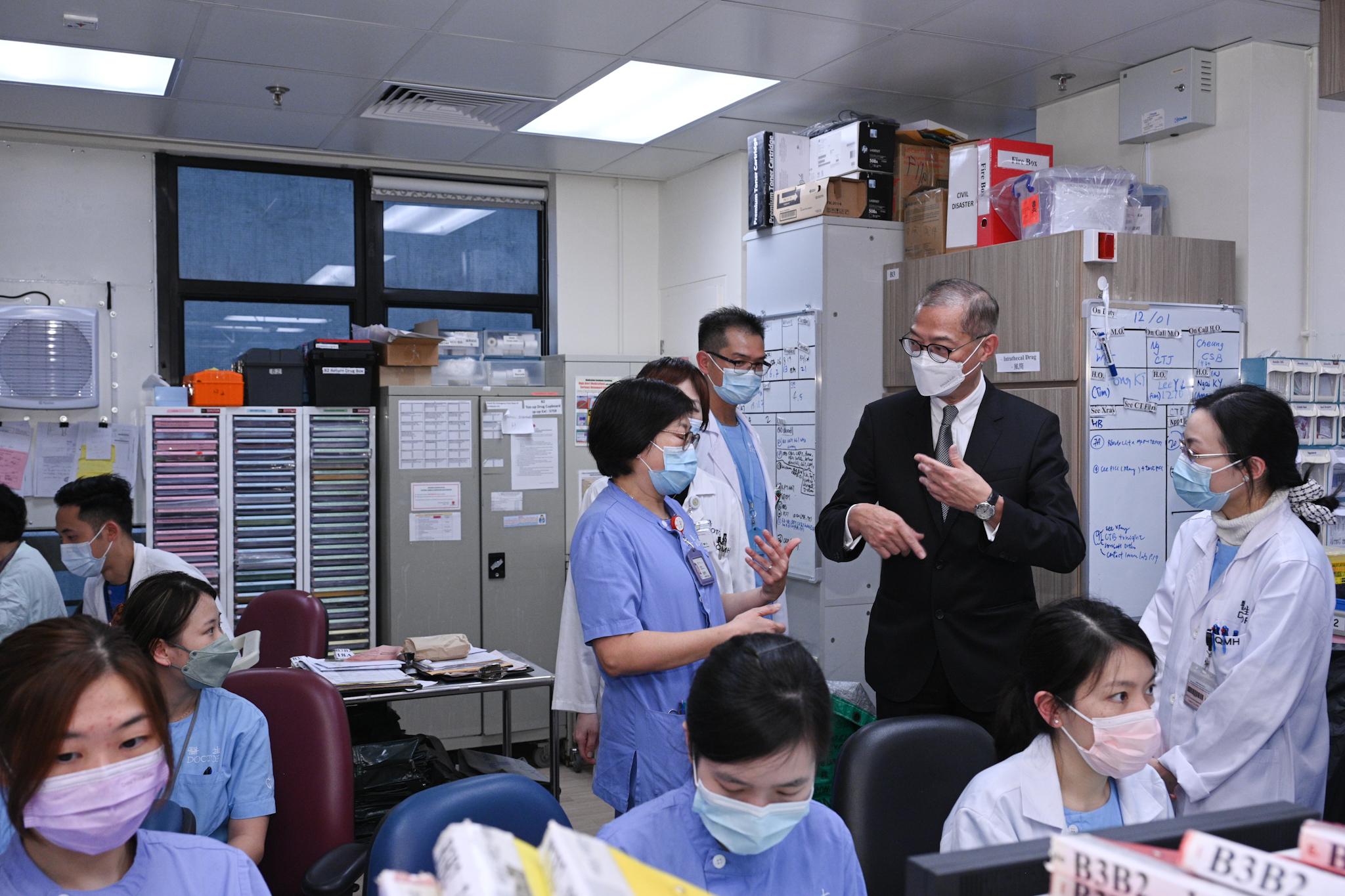 The Secretary for Health, Professor Lo Chung-mau, visited Queen Mary Hospital today (January 13). Photo shows Professor Lo (second right) receiving a briefing by frontline healthcare staff on current service situation and manpower arrangements at the hospital in response to the dual challenges posed by COVID-19 and the winter influenza.