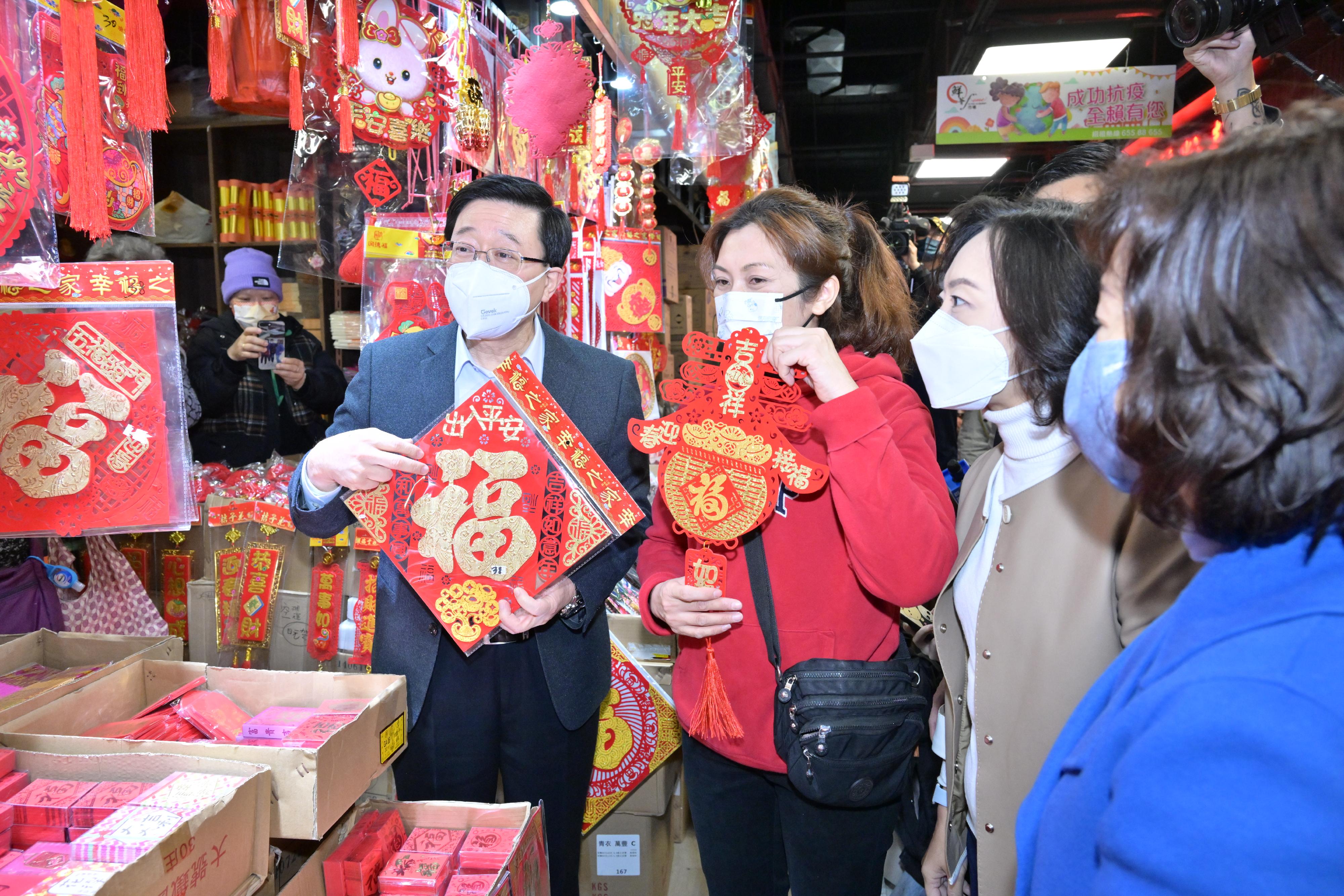 The Chief Executive, Mr John Lee, visited Cheung Hang Estate in Tsing Yi today (January 20). Photo shows Mr Lee (first left), accompanied by the Secretary for Home and Youth Affairs, Miss Alice Mak (second right) and the Director of Home Affairs, Mrs Alice Cheung (first right), visiting a market and chatting with a market stall operator to learn about her business. Mr Lee also bought spring couplets from the stall.
