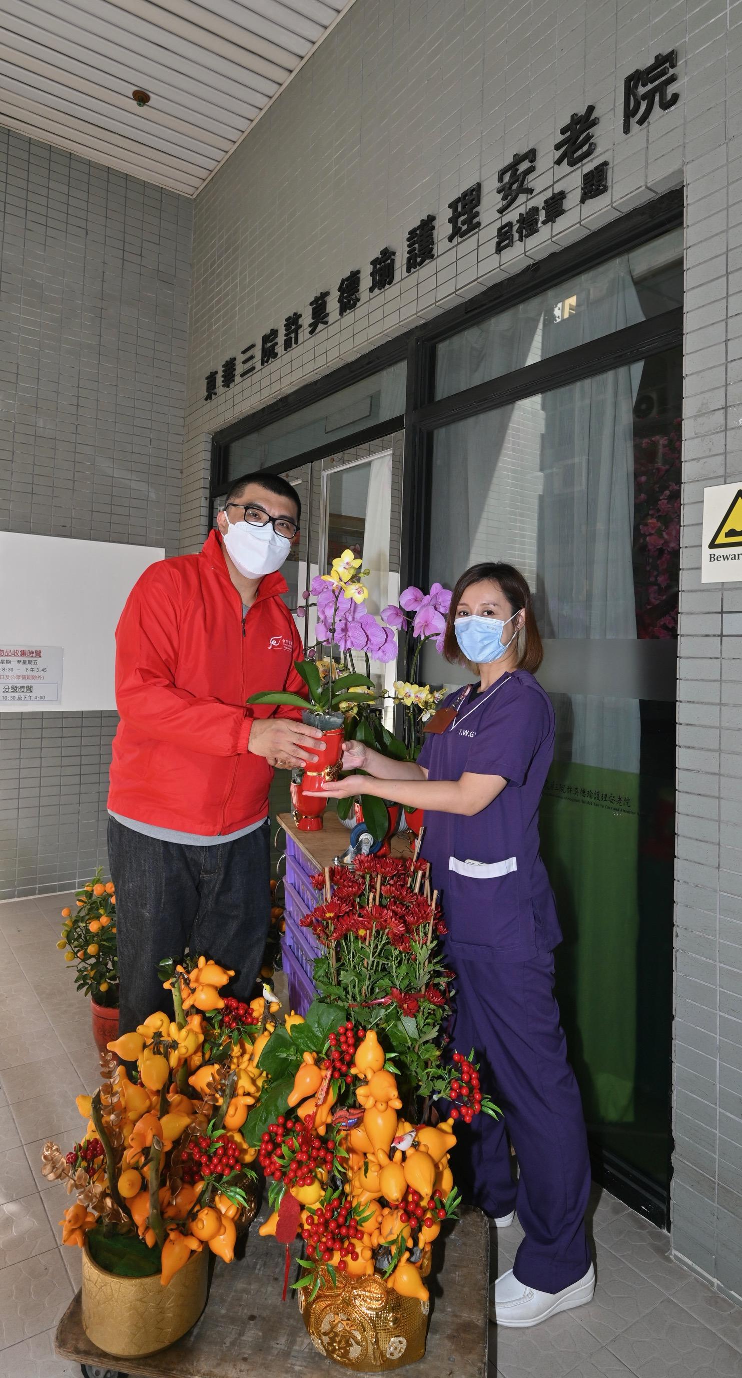 Volunteer teams of the Food and Environmental Hygiene Department today (January 22) assisted the department to deliver unsold pots of flowers and plants donated by Lunar New Year fair vendors to elderly homes/residential care homes for persons with disabilities and to public hospitals. Photo shows volunteer delivering pots of flowers to representative of a home for the elderly.