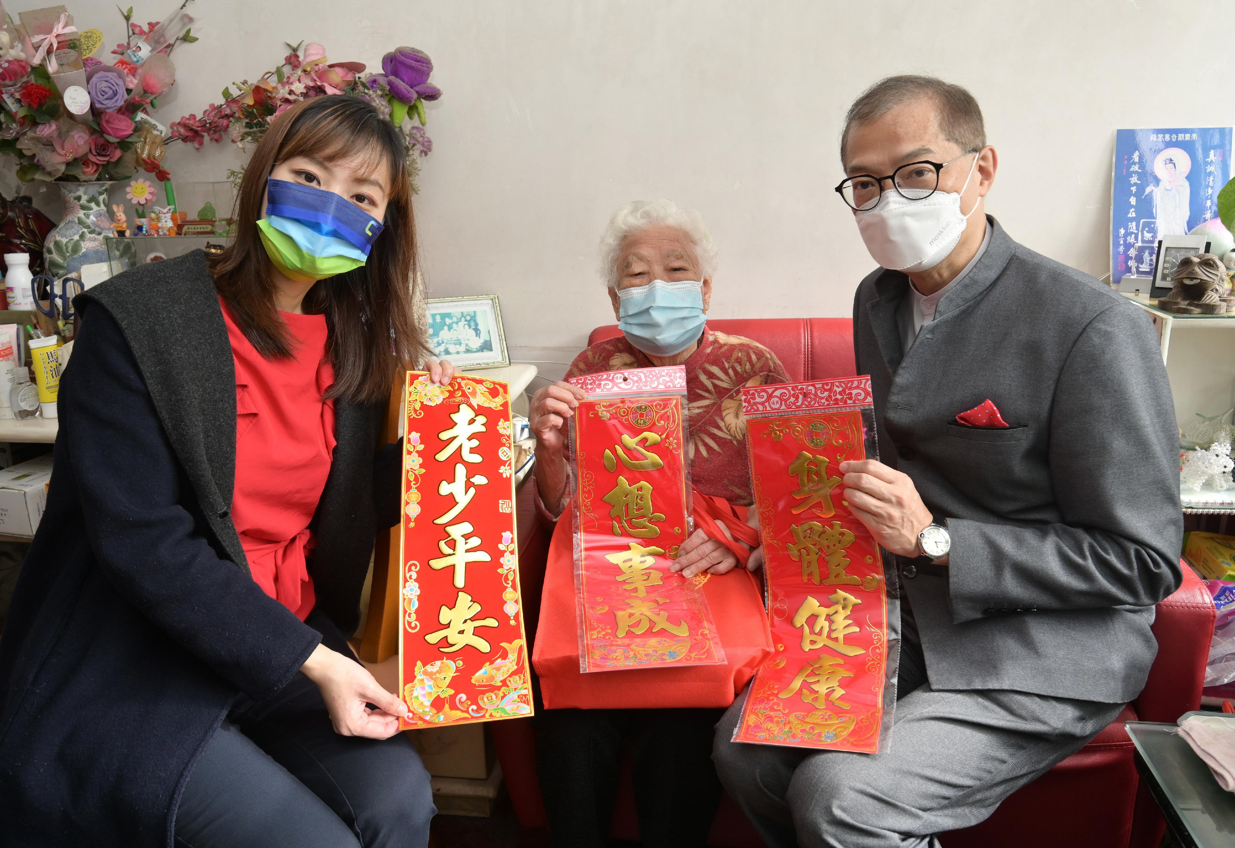 The Deputy Secretary for Justice, Mr Cheung Kwok-kwan, together with a number of the Principal Officials today (January 23) visited grass-roots families in Wong Tai Sin District to distribute blessing bags and celebrate Chinese New Year with them. Photo shows the Secretary for Health, Professor Lo Chung-mau (right) and the Acting Secretary for Innovation, Technology and Industry, Ms Lillian Cheong (left) presenting gifts to a senior and extending seasonal greetings to them on behalf of the Government.