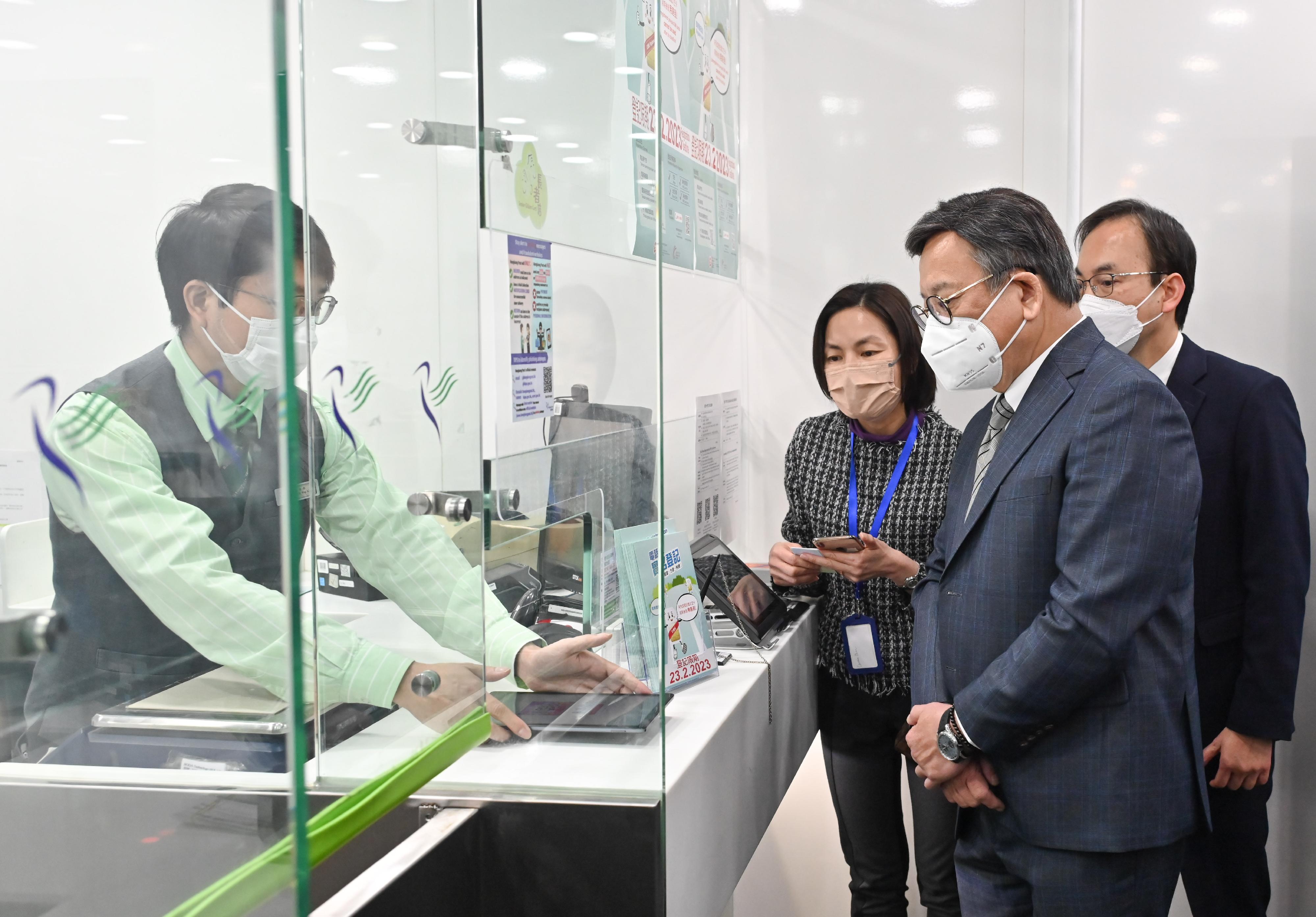 The Secretary for Commerce and Economic Development, Mr Algernon Yau, visited Wan Chai Post Office this afternoon (February 16)  to view the operation of the support service for real-name registration for SIM cards. Photo shows Mr Yau (second right), accompanied by the Director-General of Communications, Mr Chaucer Leung (first right), being briefed by a representative of the Office of the Communications Authority on the support service.