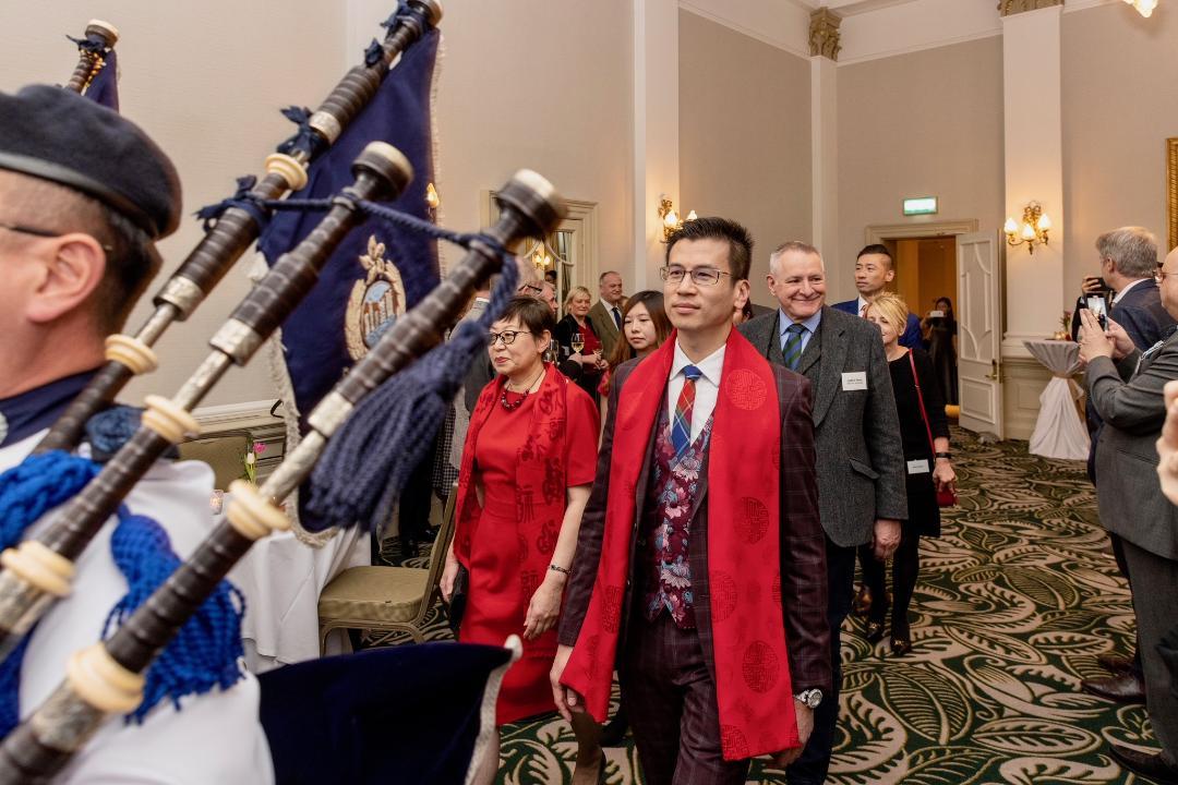 The Hong Kong Economic and Trade Office, London (London ETO) hosted a reception in Edinburgh, the United Kingdom, on February 27 (London time) for celebrating the Year of the Rabbit. Photo shows the bagpipers from the Hong Kong Police Band leading in the Director-General of the London ETO, Mr Gilford Law (fourth left); the Acting Consul General of the People’s Republic of China in Edinburgh, Ms Hou Danna (second left); and other officiating guests.