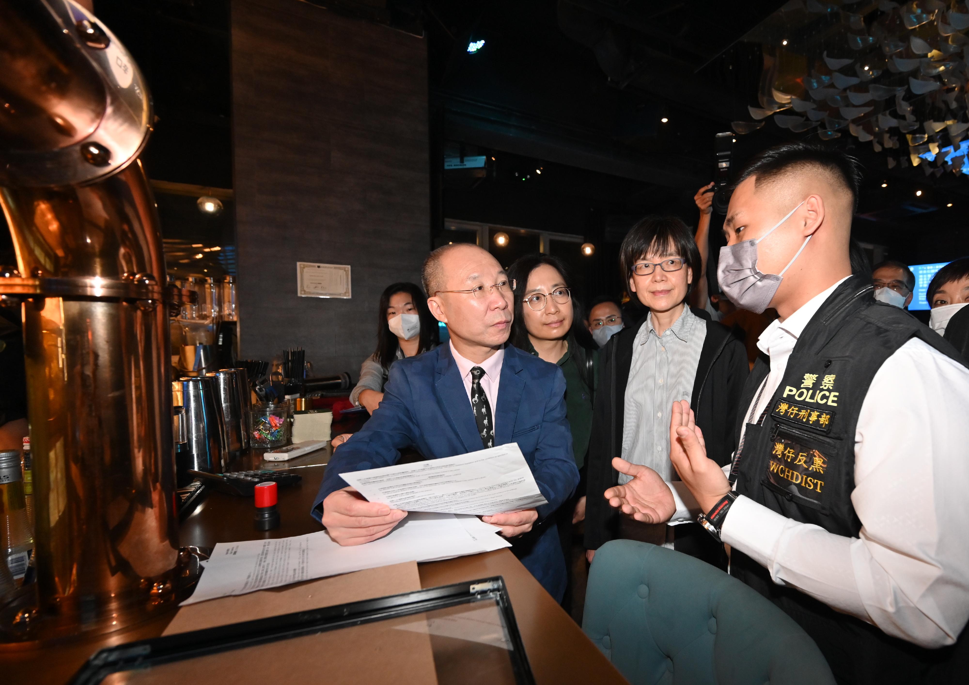 Members of the Liquor Licensing Board, led by the Board Chairman, Dr Wong Kong-tin, visited a number of different types of premises with liquor licences in Wan Chai District and Tsim Sha Tsui District in the small hours today (March 12) to learn more about the operation of the premises and enforcement action by the Police. Photo shows (from left) Dr Wong; the Director of Food and Environmental Hygiene, Ms Irene Young; and the Permanent Secretary for Environment and Ecology (Food), Miss Vivian Lau, being briefed by a representative of the Police.
