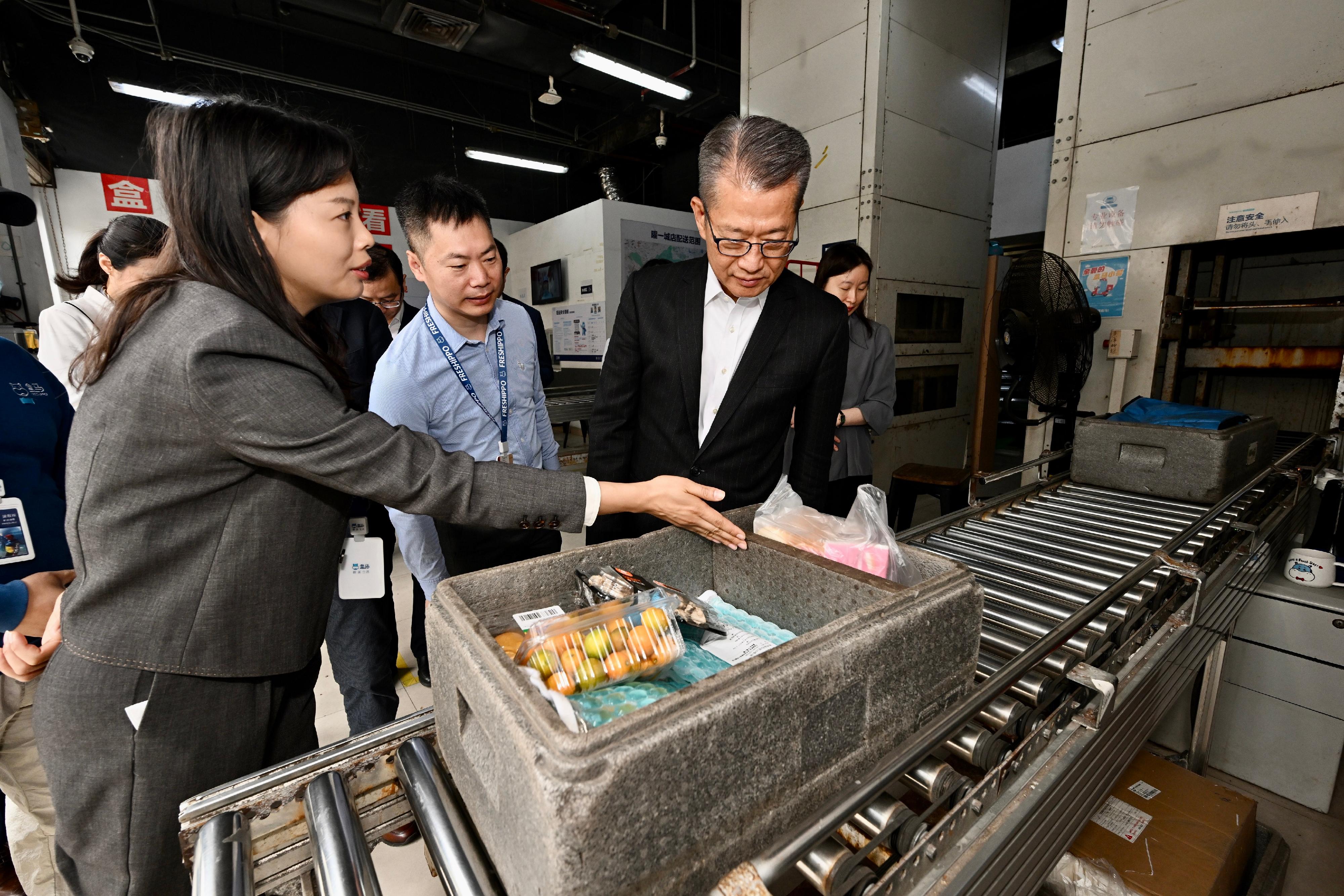財政司司長陳茂波（右）今日（三月十五日）到訪廣州市的盒馬網路科技有限公司，了解該公司如何應用大數據、人工智能和物流科技，加速新鮮食品和產品的配送。