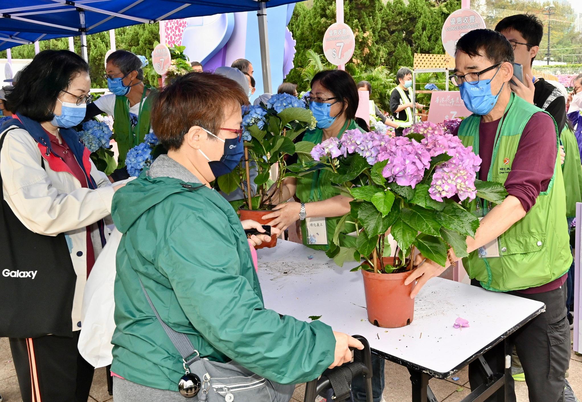 The Green Recycling Day activities for the Hong Kong Flower Show organised by the Leisure and Cultural Services Department were held today (March 20) and will continue tomorrow (March 21) to reinforce green measures and reduce waste, reflecting the department's commitment to implementing green measures for environmental protection in its large-scale events. Photo shows volunteers distributing pots of flowers to the public.