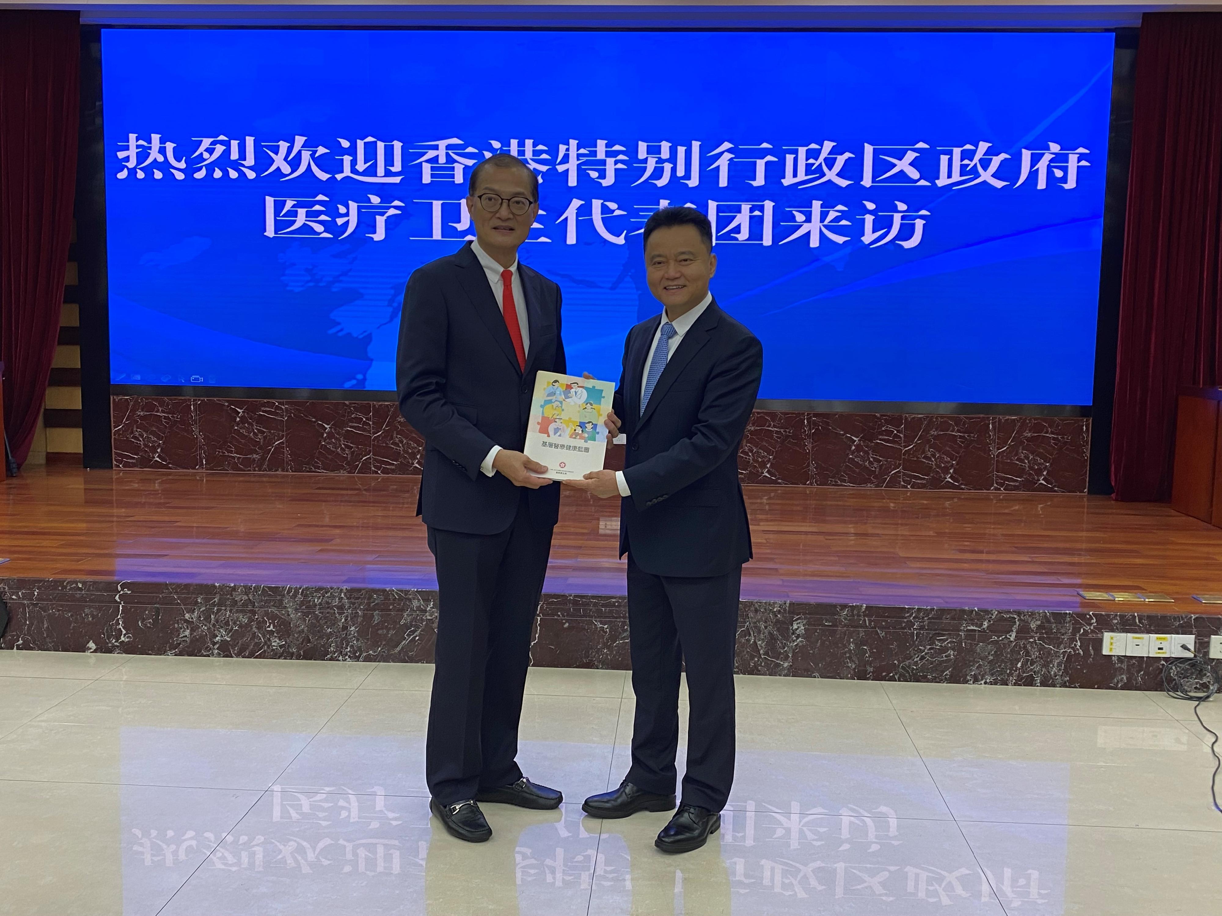 The Secretary for Health, Professor Lo Chung-mau, led his delegation to visit the Health Commission of Guangdong Province today (March 29). Photo shows Professor Lo (left) presenting the Primary Healthcare Blueprint released last year to the Party Secretary and Director of the Health Commission of Guangdong Province, Mr Zhu Hong (right).