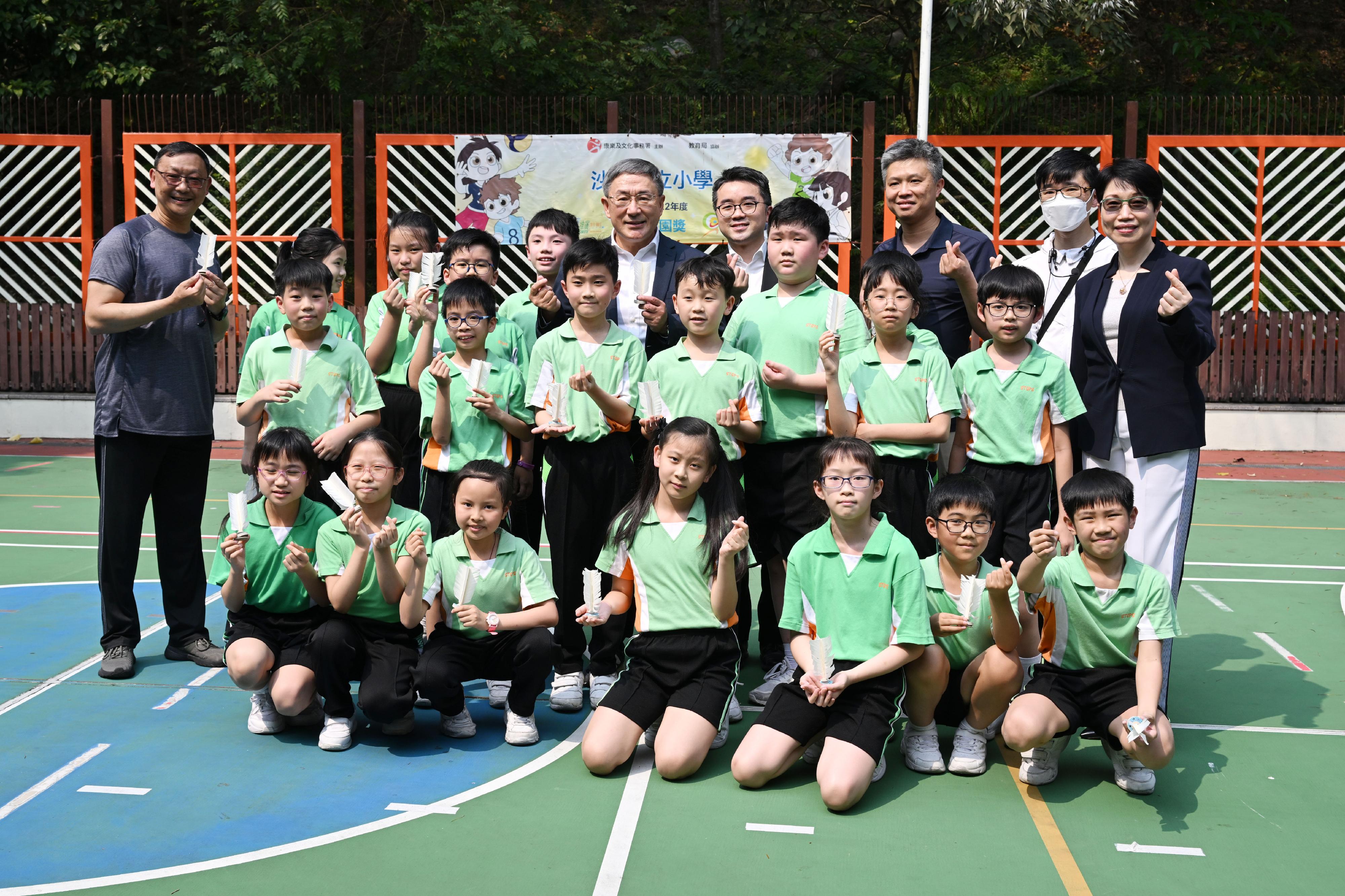 The Deputy Chief Secretary for Administration, Mr Cheuk Wing-hing (back row, centre), the Acting Secretary for Education, Mr Sze Chun-fai (back row, fourth right), and the school principal Ms Ellen Wong (back row, first right) join a group photo with the students taking part in a workshop on shuttlecock kicking at Shatin Government Primary School today (April 13).