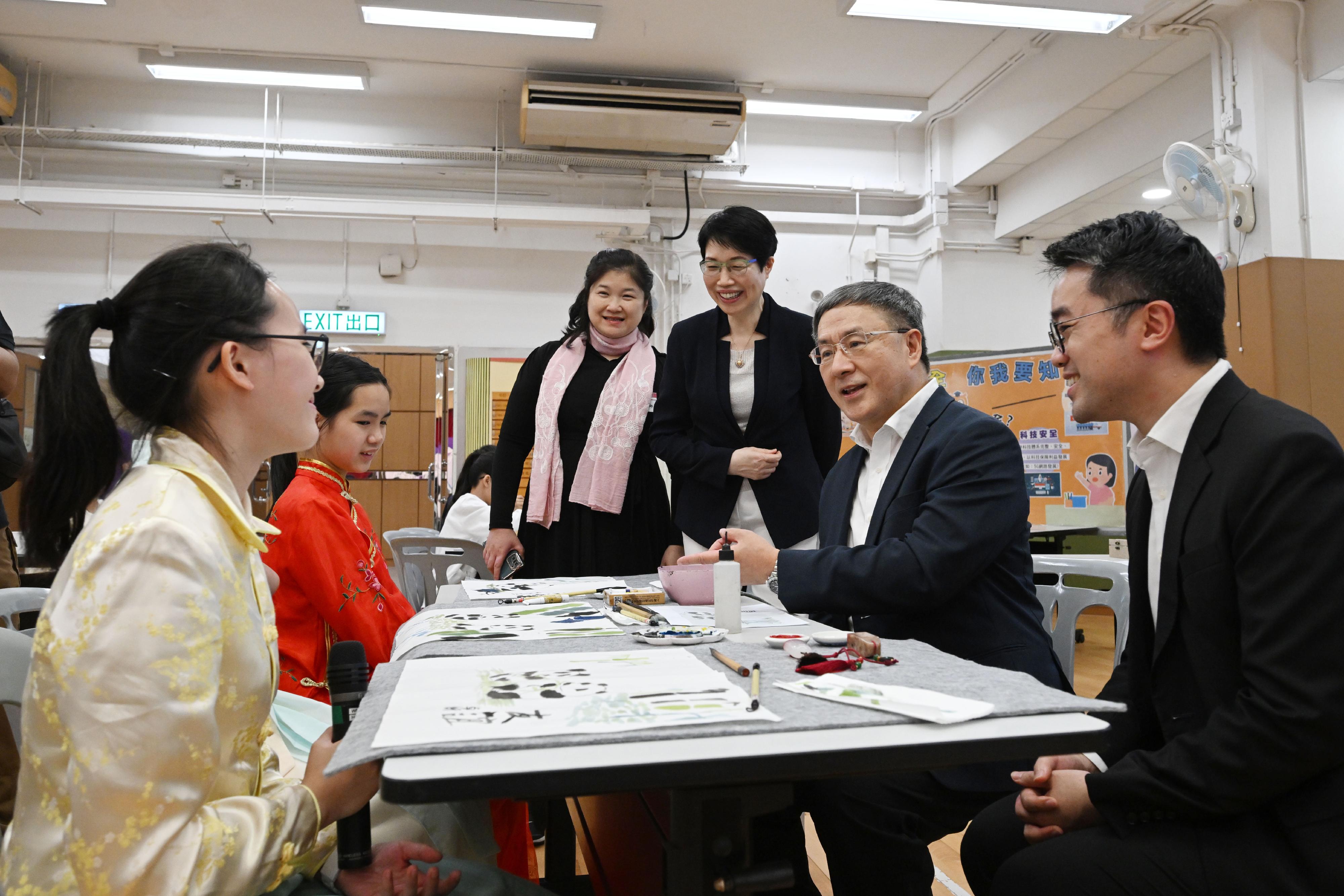 The Deputy Chief Secretary for Administration, Mr Cheuk Wing-hing (second right), learns more about students' achievements at a workshop on traditional Chinese painting at Shatin Government Primary School today (April 13). Next to Mr Cheuk is the Acting Secretary for Education, Mr Sze Chun-fai (first right).