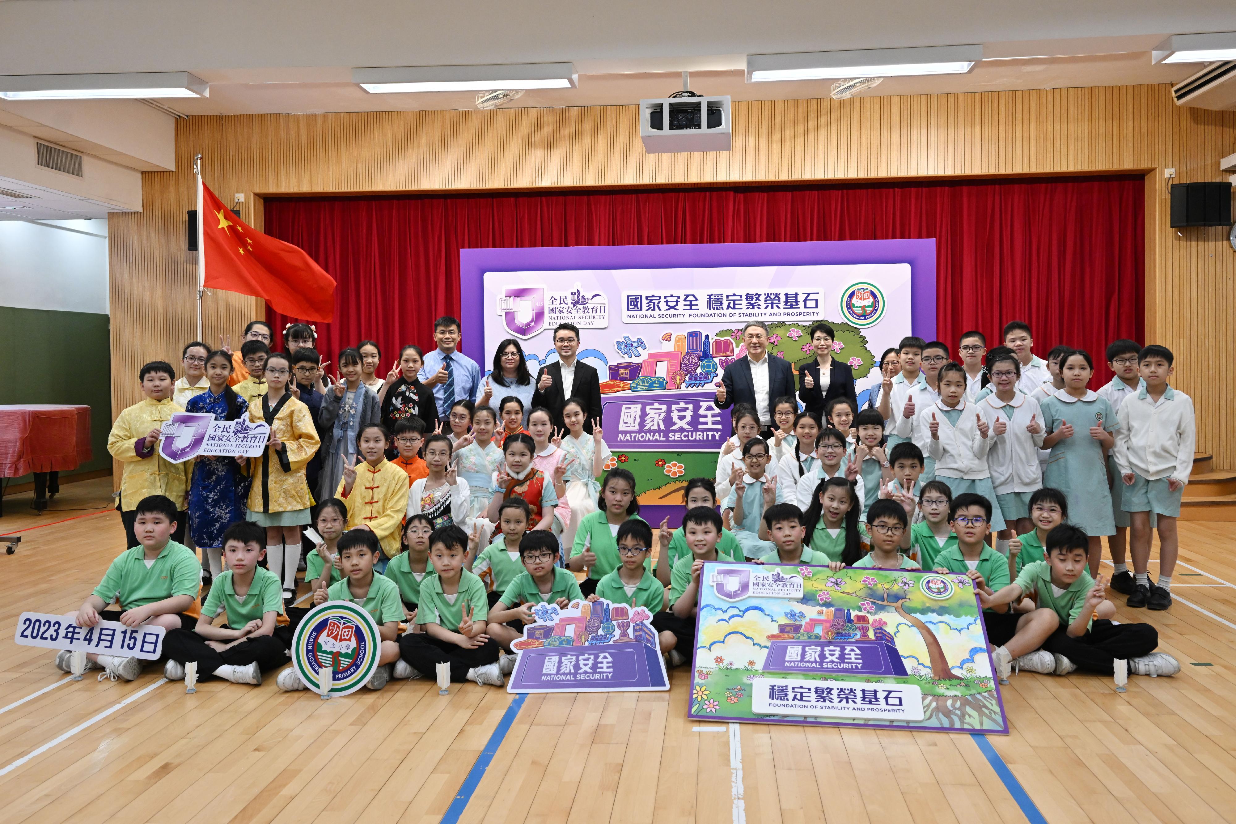 The Deputy Chief Secretary for Administration, Mr Cheuk Wing-hing, and the Acting Secretary for Education, Mr Sze Chun-fai, join a group photo with the students and the school principal Ms Ellen Wong in front of a mural themed "National Security: Foundation of Stability and Prosperity" at Shatin Government Primary School today (April 13).