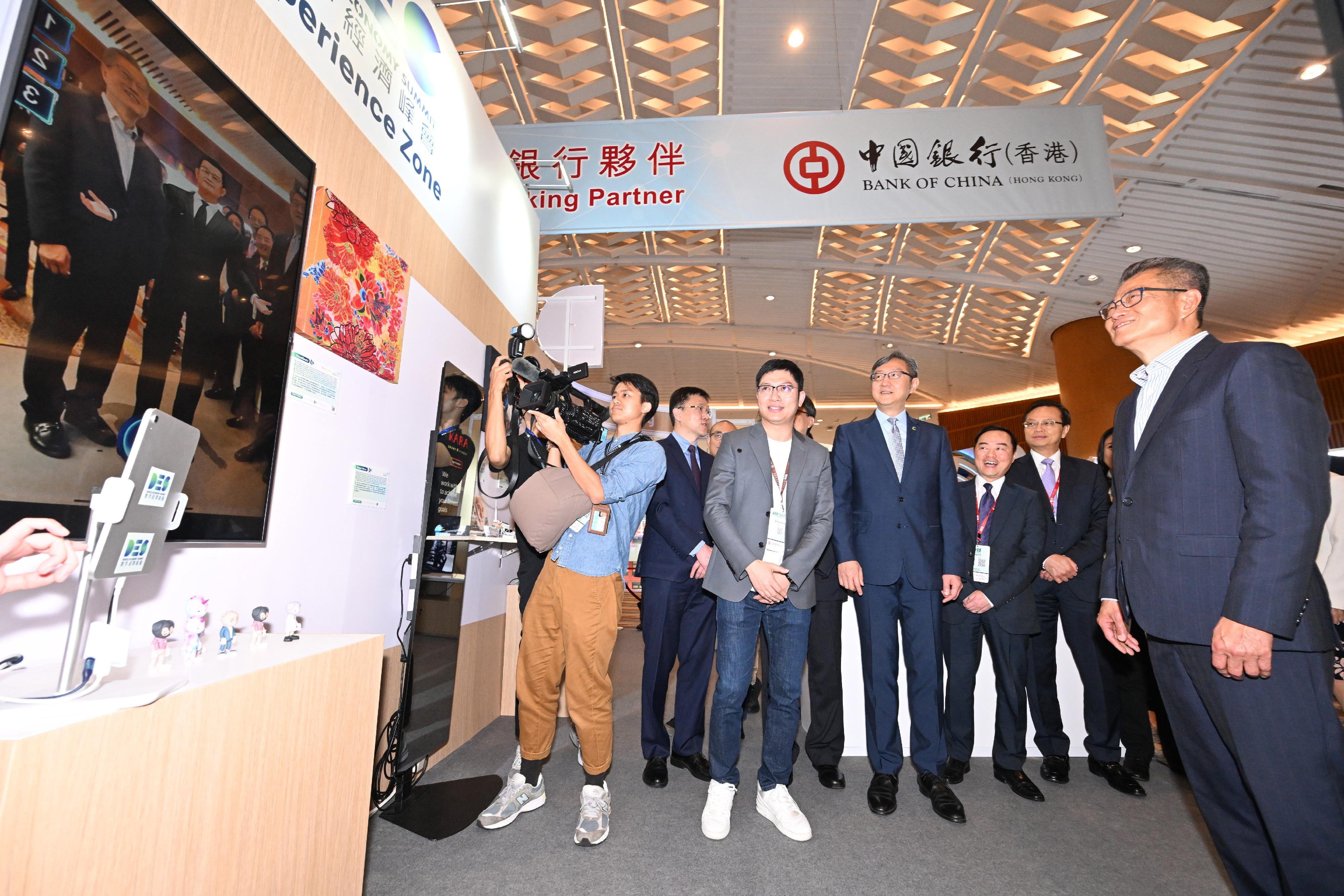 The Financial Secretary, Mr Paul Chan (first right), tours the exhibition before attending the FinTech Forum of the Digital Economy Summit 2023 today (April 14). 