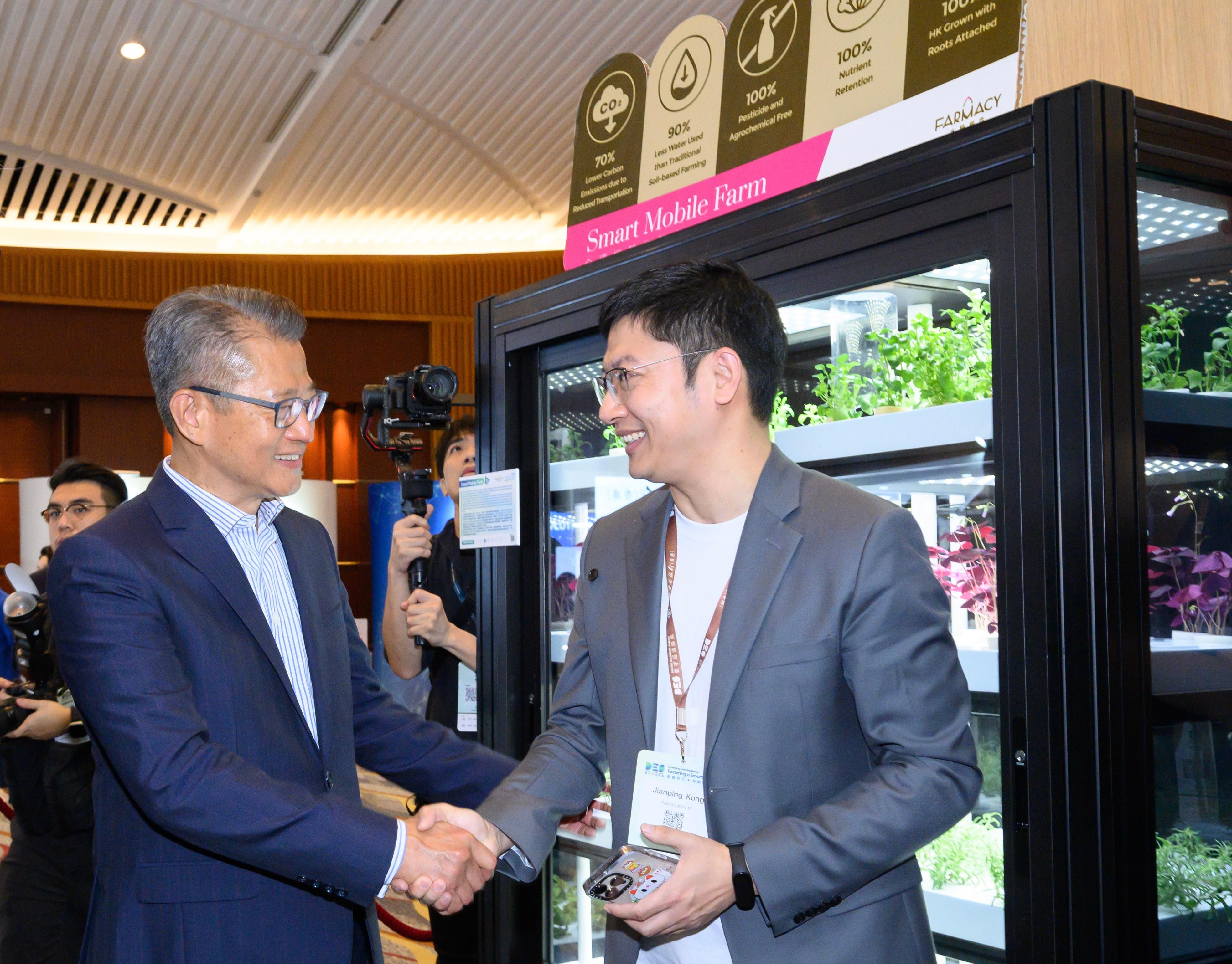 The Financial Secretary, Mr Paul Chan (left), tours the exhibition before attending the FinTech Forum of the Digital Economy Summit 2023 today (April 14). 