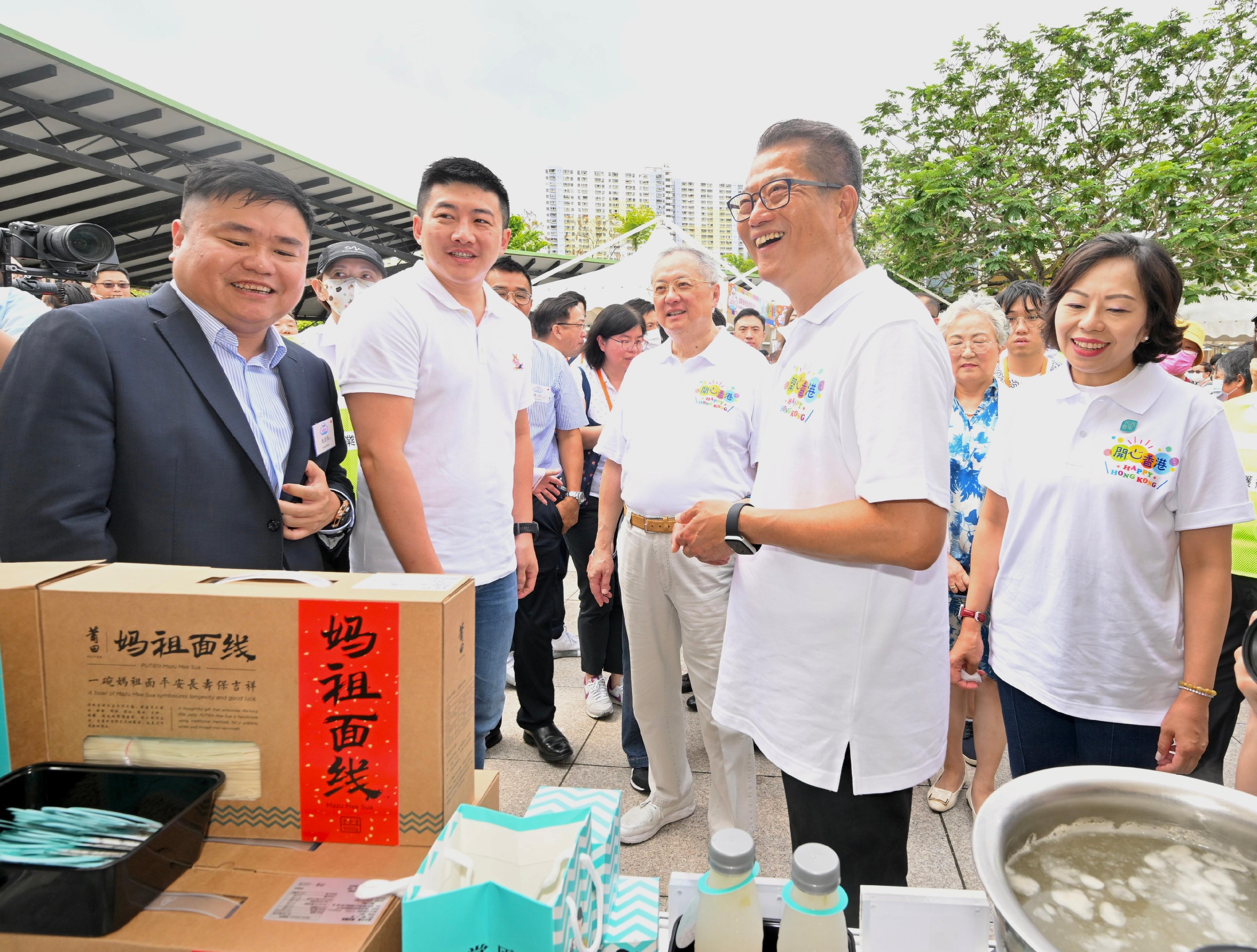 The Financial Secretary, Mr Paul Chan, officiated at the opening ceremony of the second "Happy Hong Kong" Gourmet Marketplace today (May 6). Photo shows Mr Chan (second right), accompanied by the Secretary for Home and Youth Affairs, Miss Alice Mak (first right), and Non-official Member of the Executive Council, Legislative Council Member (Catering) Mr Tommy Cheung (third right), exchanging views with an exhibitor.