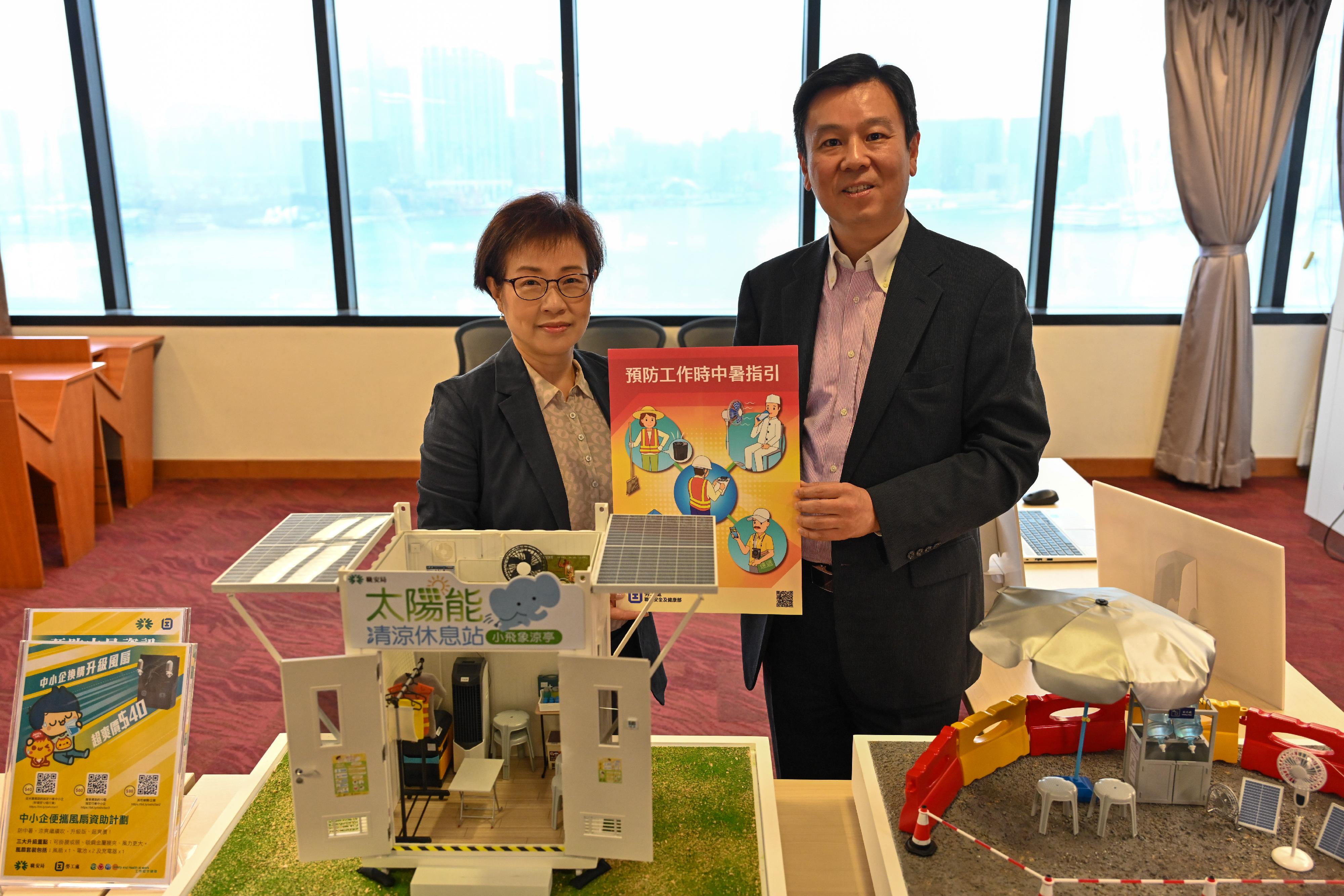 The Deputy Commissioner for Labour (Occupational Safety and Health), Mr Vincent Fung (right), and the General Manager of the Occupational Safety and Health Council, Ms Catherine Wong (left), display the Guidance Notes on Prevention of Heat Stroke at Work and models of heat stroke prevention facilities. 