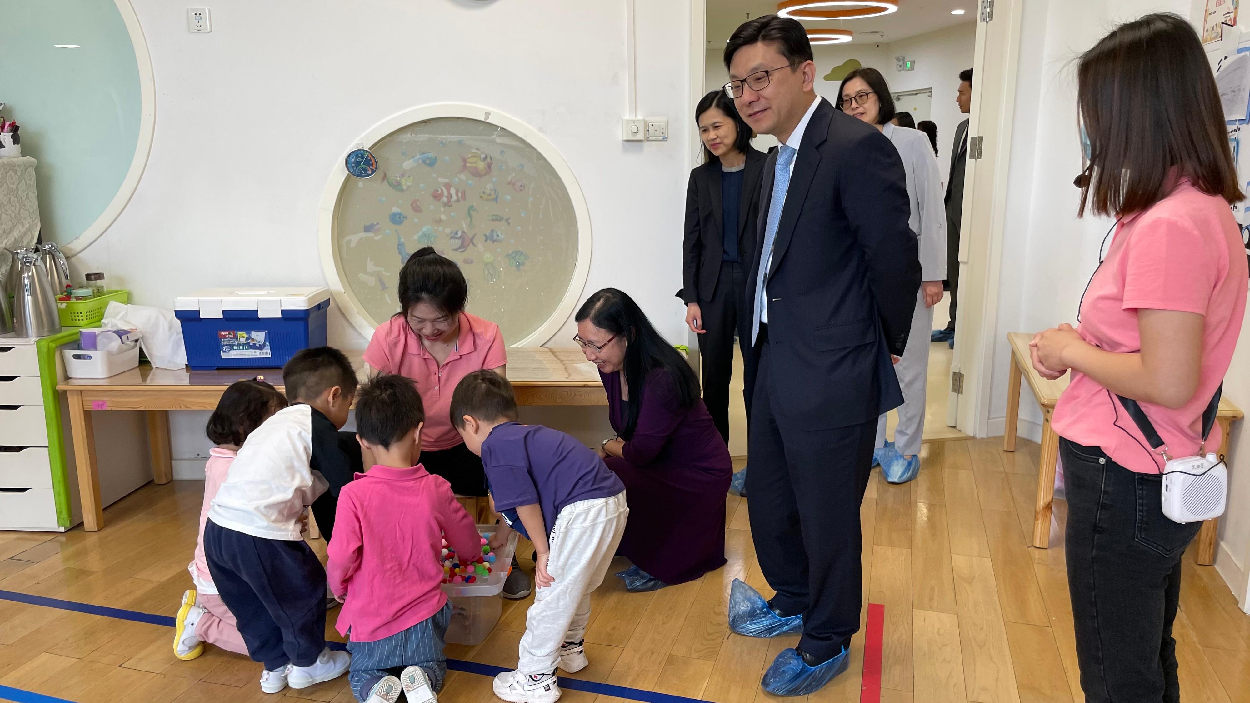 The Secretary for Labour and Welfare, Mr Chris Sun, today (May 9) continued his visit in Beijing. The Permanent Secretary for Labour and Welfare, Ms Alice Lau, also joined the visit. Photo shows Mr Sun (standing, second right) and Ms Lau (kneeling, first right) watching children receiving care services while playing, during their visit to an occasional child care facility in Beijing this morning.