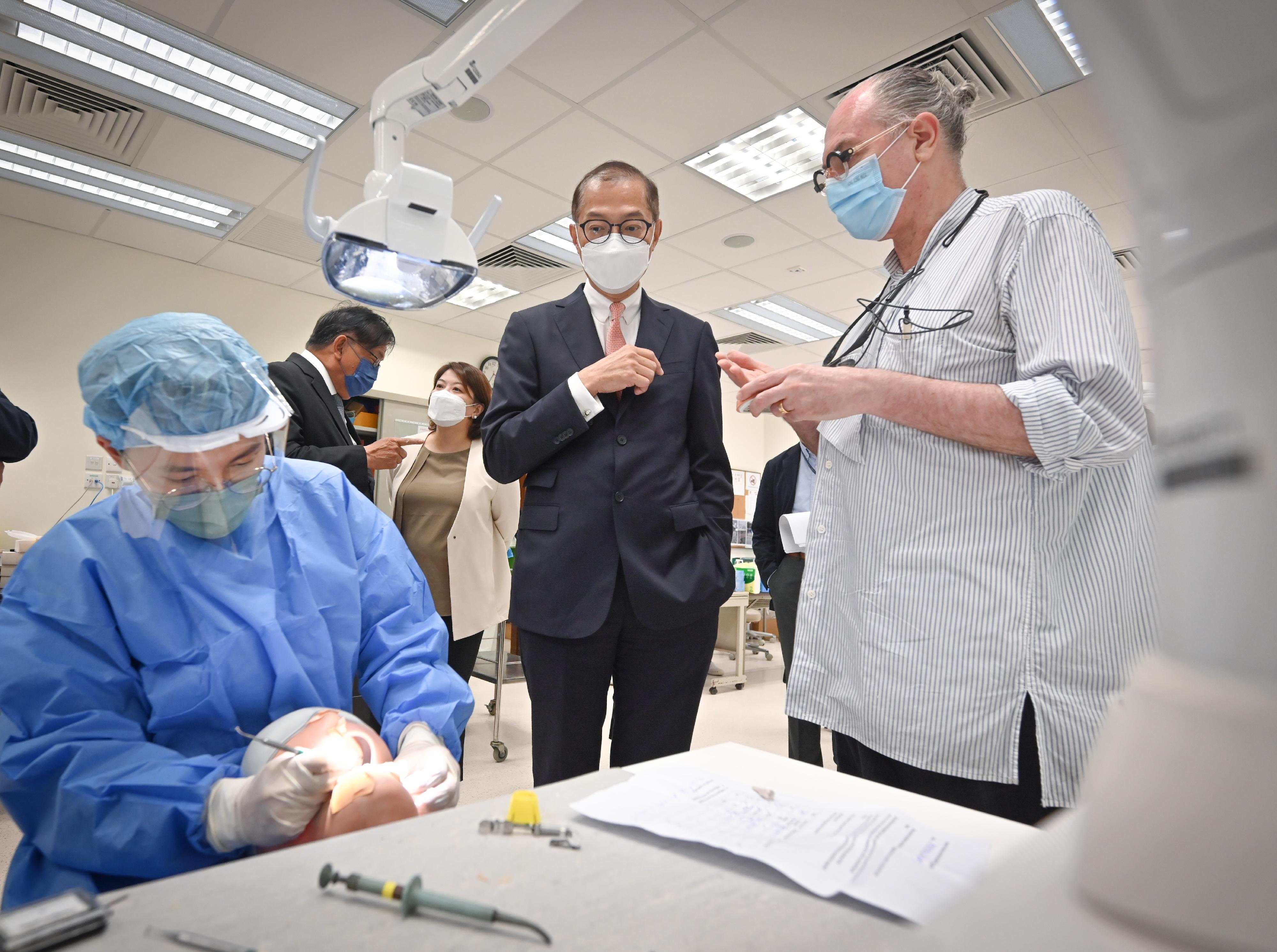 医务卫生局局长卢宠茂教授（中）今日（五月九日）在菲腊牙科医院听取该院模拟实验室的职员介绍其工作情况。
