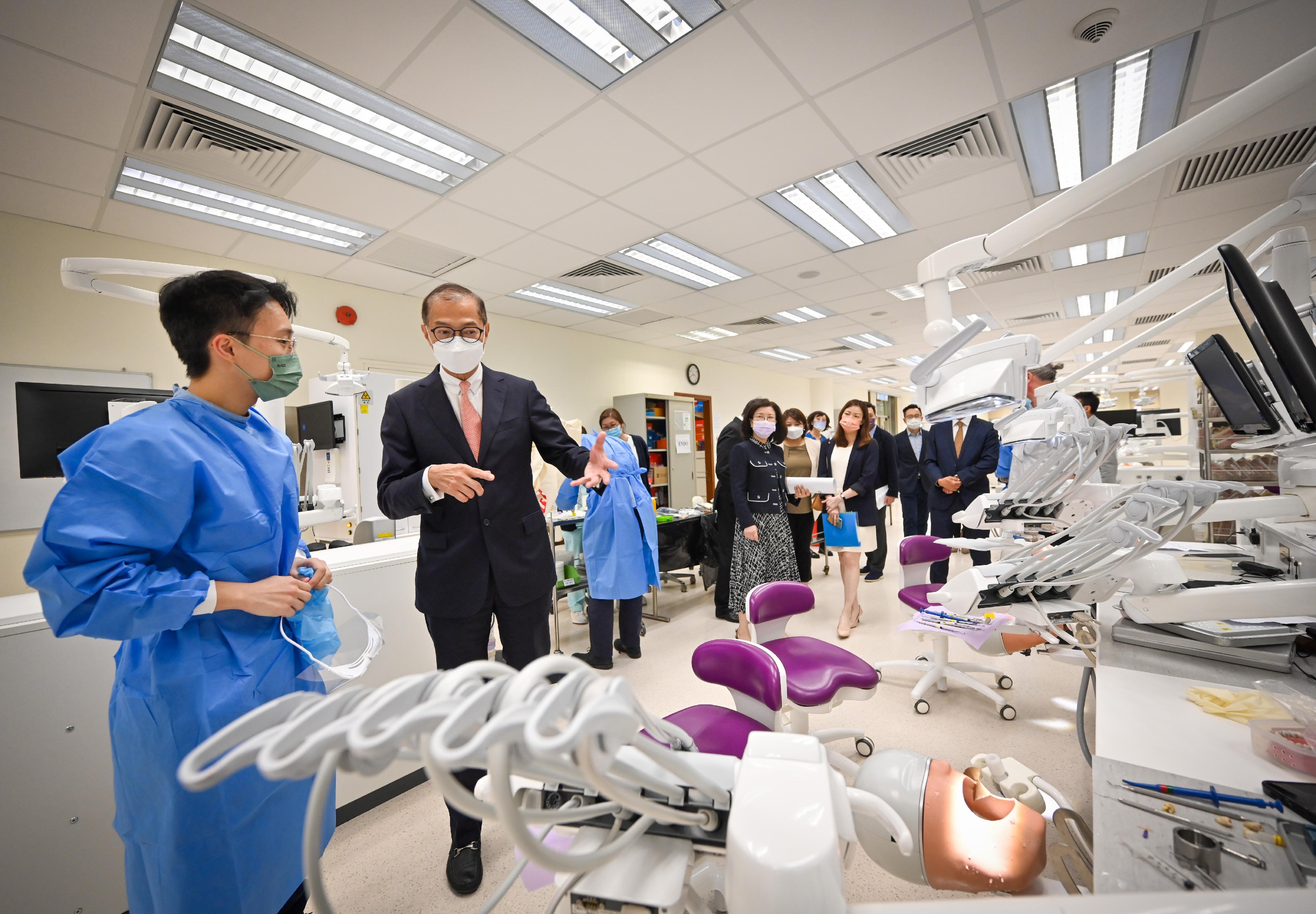 During his visit to the simulation laboratory of the Prince Philip Dental Hospital today (May 9), the Secretary for Health, Professor Lo Chung-mau (second left), chatted with a student to get a better understanding of his learning experience there.