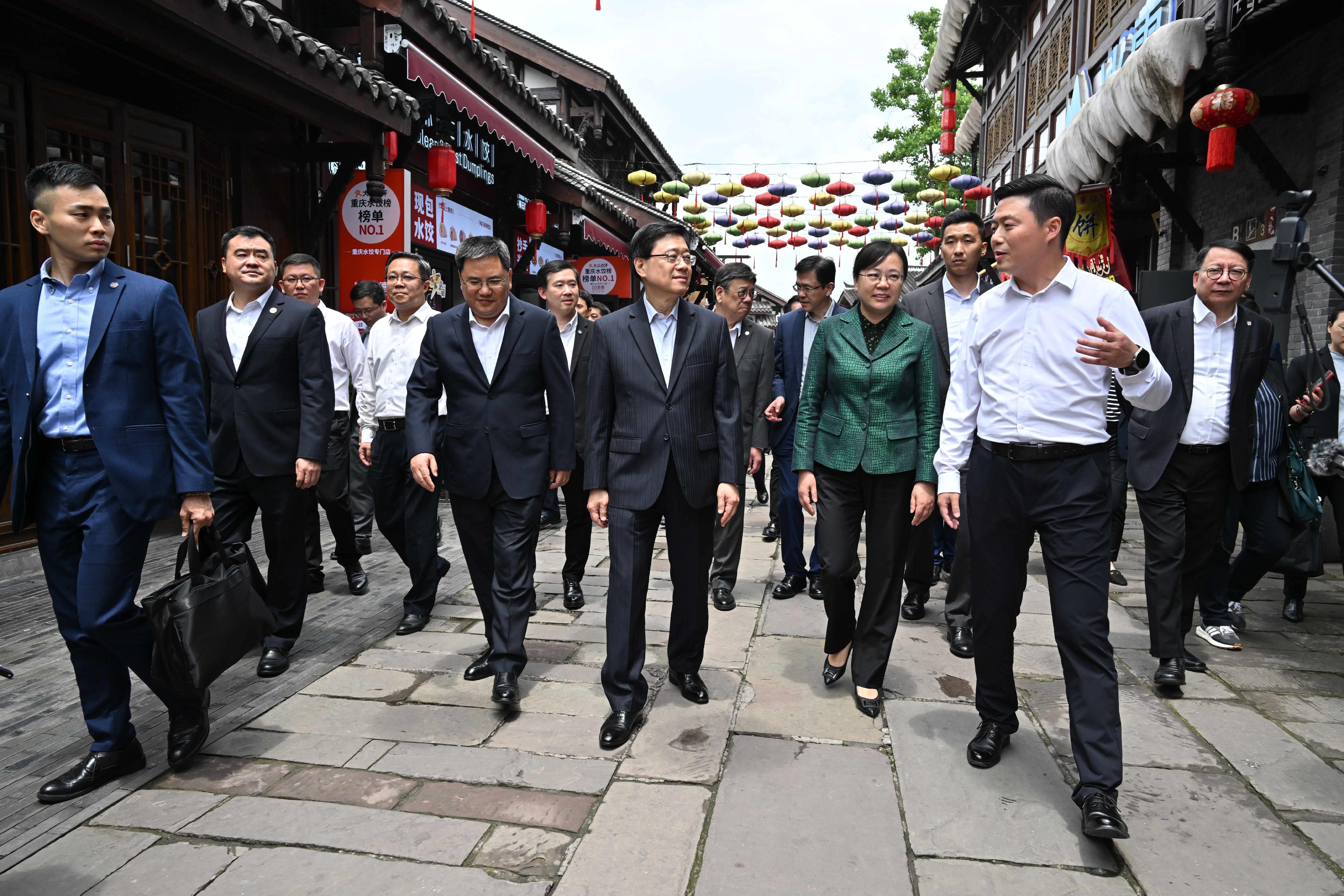 The Chief Executive, Mr John Lee (front row, third right), and Vice Mayor of Chongqing Municipal People's Government Ms Zhang Guozhi (front row, second right) visit the Ciqikou Ancient Town in Chongqing today (May 11). Looking on is the Chief Secretary for Administration, Mr Chan Kwok-ki (second row, first right).