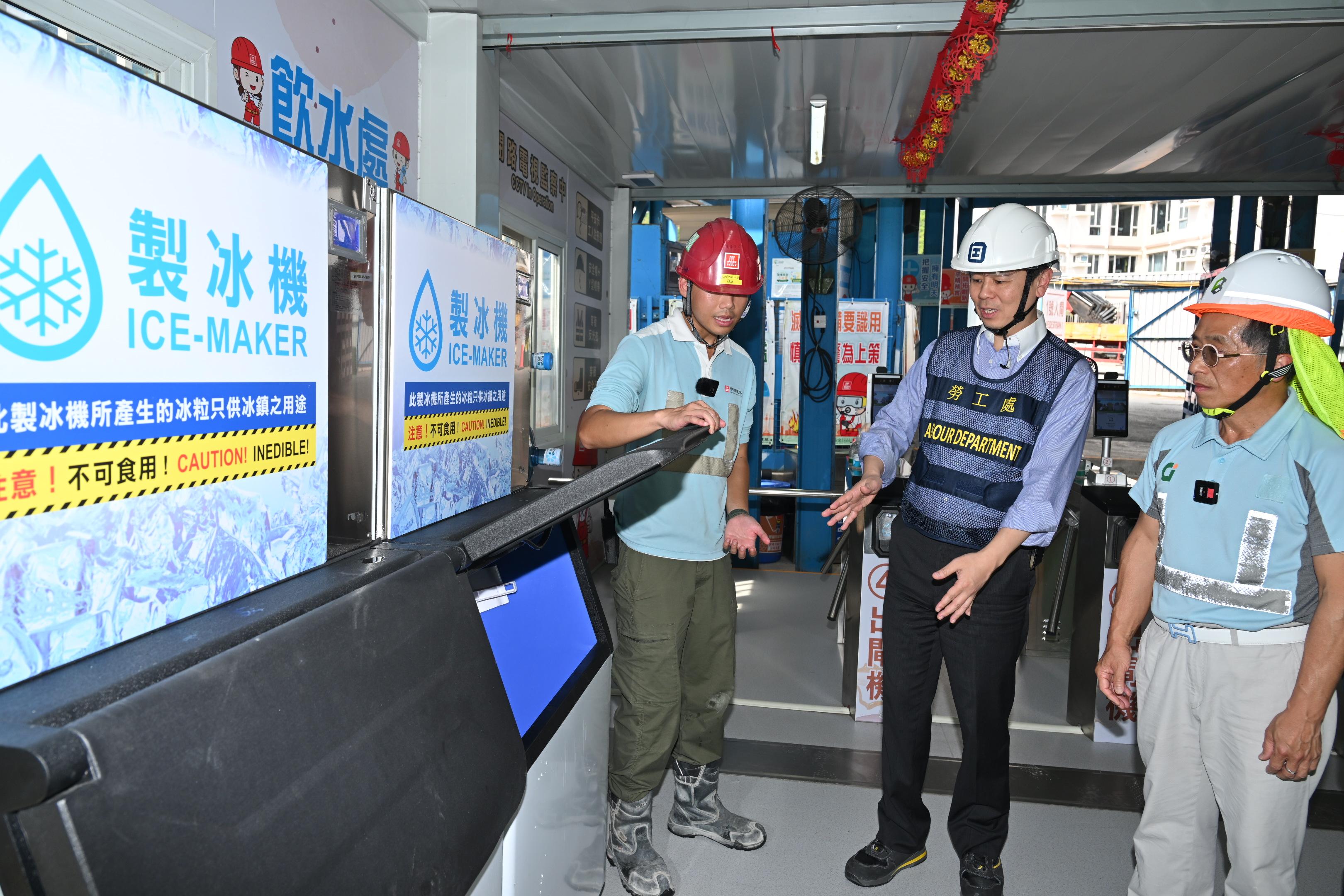 The Labour Department and representatives of the construction industry promoted prevention of heat stroke at work at a public works site in Tseung Kwan O today (June 9). Photo shows the Acting Commissioner for Labour, Mr Vincent Fung (centre), and the Chairman of the Construction Industry Council, Mr Thomas Ho (first right), having a look at the ice-maker at the construction site.

