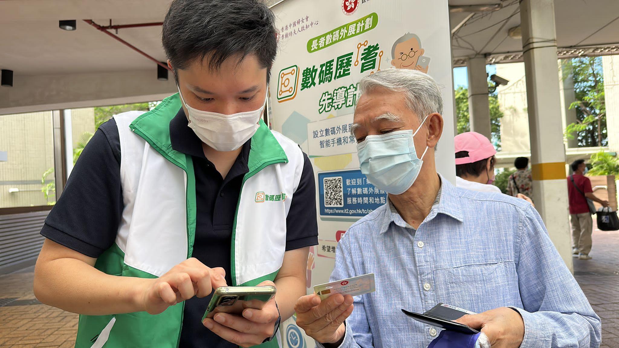 政府资讯科技总监办公室（资科办）今日（六月十四日）宣布新一轮长者数码外展计划已经展开。图示长者在上一轮长者数码外展计划中于资科办与推行机构设立的流动外展服务站向工作人员查询有关使用智能手机的问题。