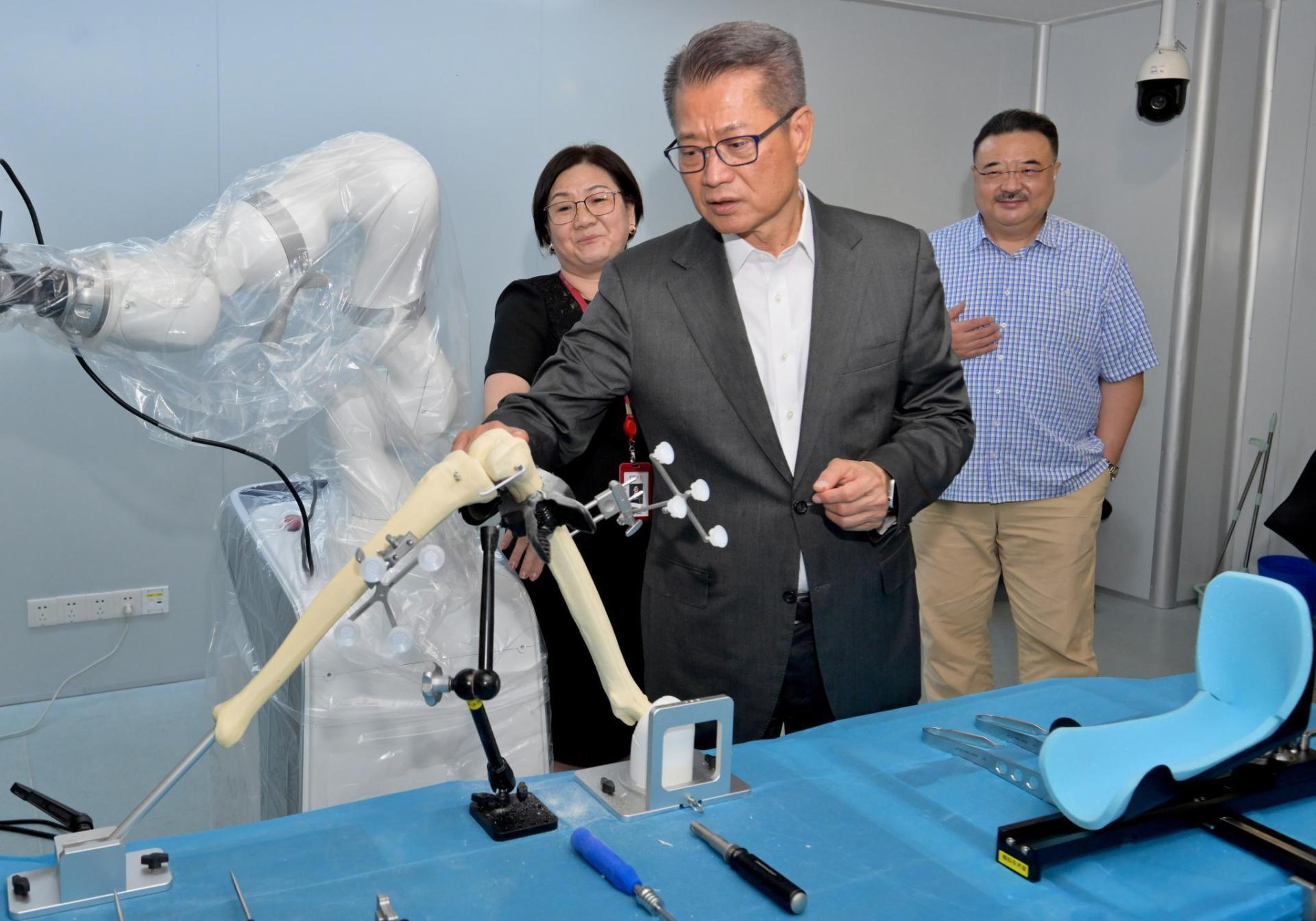 財政司司長陳茂波今日（六月十九日）到訪深圳。圖示陳茂波（中）參觀一家研發和製造手術機械人和高端醫療裝備的企業。