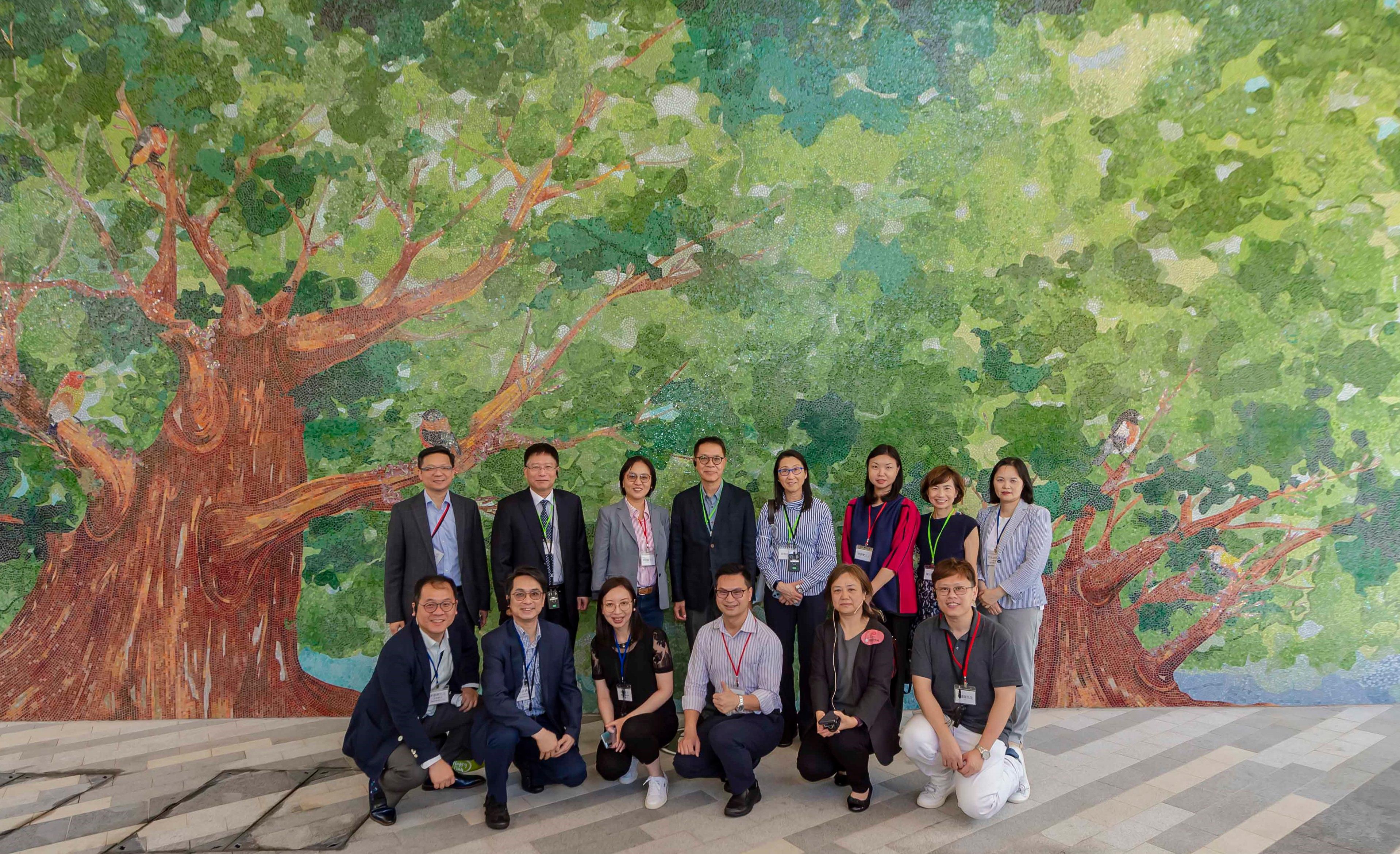 Members of the Hong Kong Housing Authority (HA) and its Commercial Properties Committee (CPC) today (June 20) visited the commercial facilities at the HA's Queens Hill Estate in Fanling. Photo shows the Chairman of the HA's CPC, Ms Serena Lau (back row, third left), members of the HA/CPC and officials of the Housing Department in front of a mural in the estate named "The Trees of Life". 