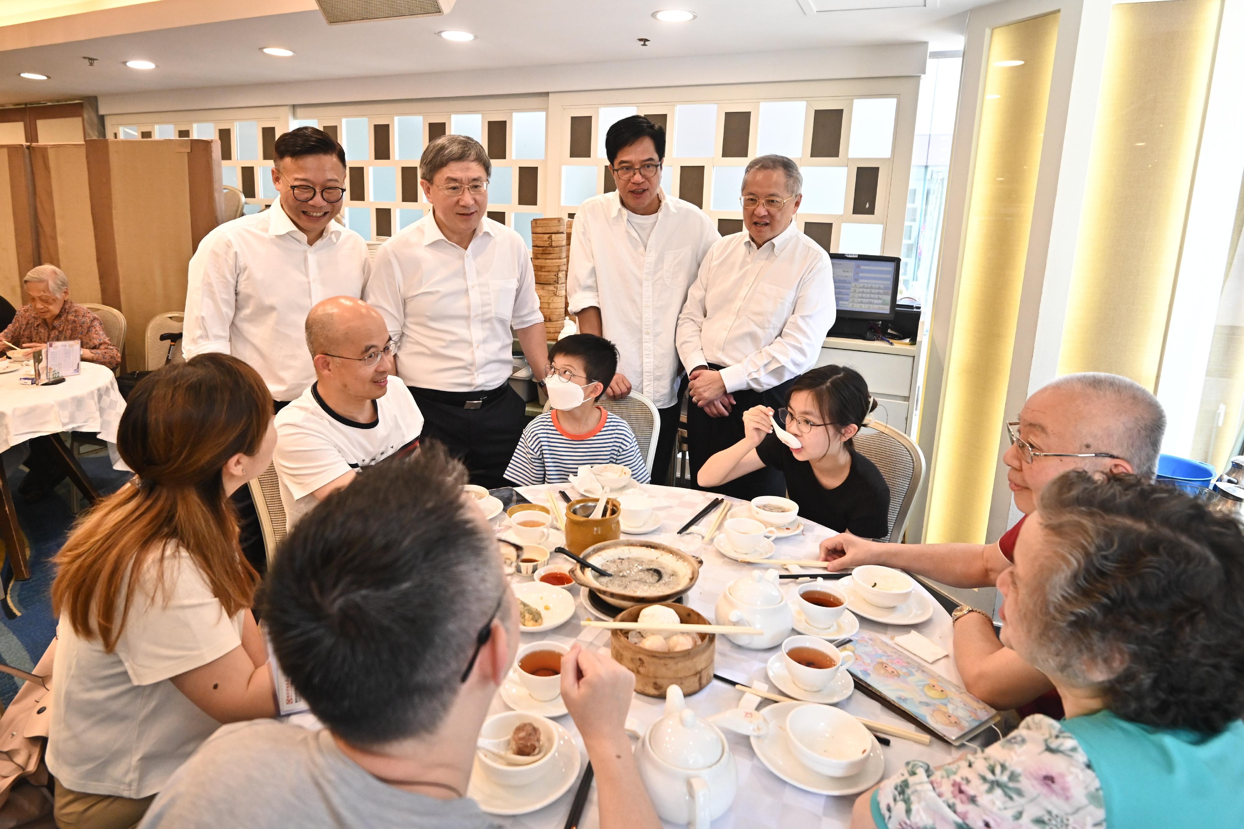 The Deputy Chief Secretary for Administration, Mr Cheuk Wing-hing (back row, left); the Deputy Financial Secretary, Mr Michael Wong (back row, centre); and the Deputy Secretary for Justice, Mr Cheung Kwok-kwan (back row, right), chat with members of the public at a North Point restaurant today (July 1). Looking on is the Legislative Council Member (Catering), Mr Tommy Cheung (back row, first right).