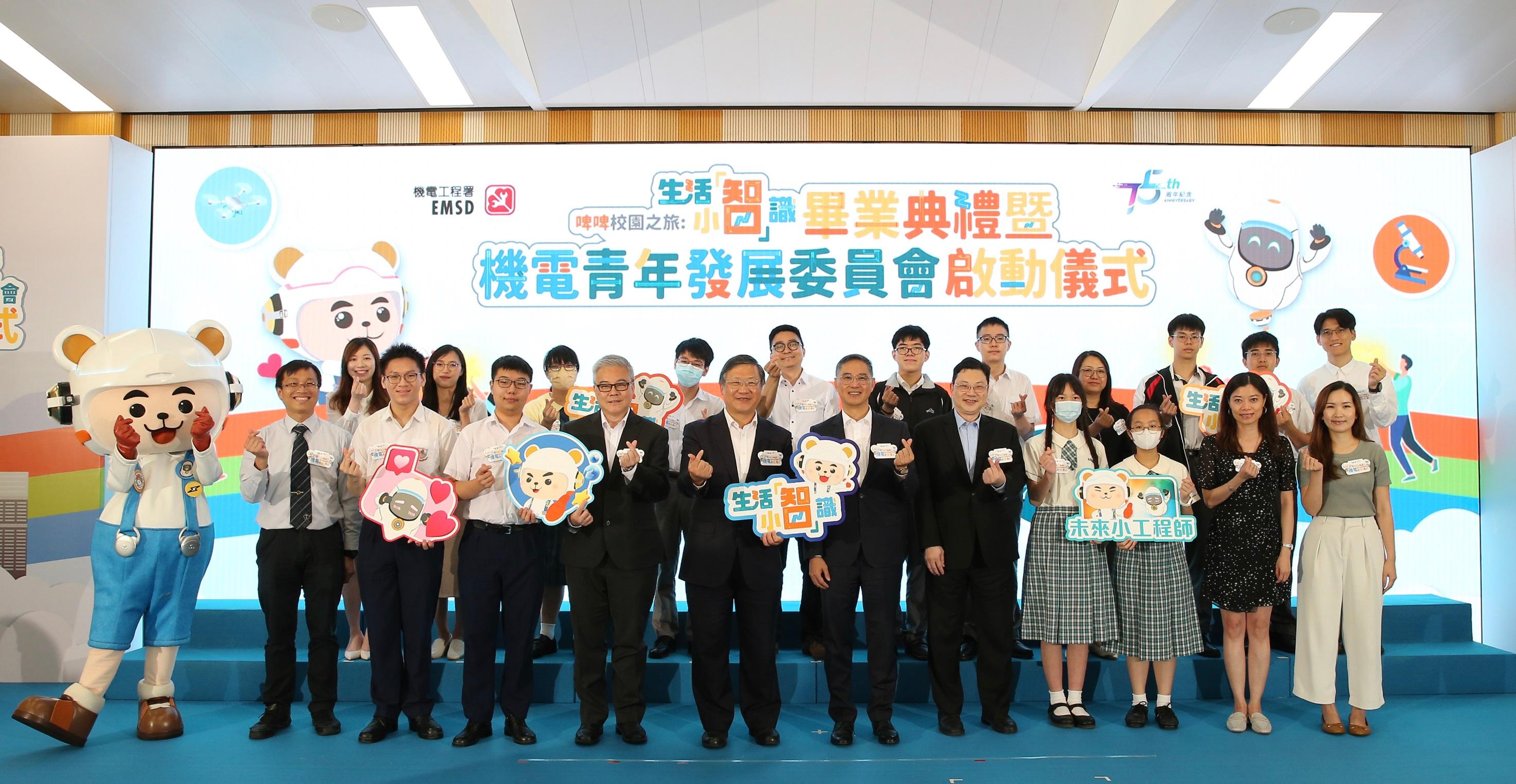 The Electrical and Mechanical Services Department (EMSD) held the "Witty Bear Campus Tour – EMbrace Smart Living in Daily Life" graduation ceremony and the E&M Youth Development Committee launching ceremony today (July 6). Photo shows the Permanent Secretary for Development (Works), Mr Ricky Lau (first row, sixth right); the Director of Electrical and Mechanical Services Department, Mr Eric Pang (first row, seventh right); Witty Bear; participants of the pilot STEM education programme "Witty Bear Campus Tour – EMbrace Smart Living in Daily Life"; school representatives and young engineers of the EMSD at the ceremony.