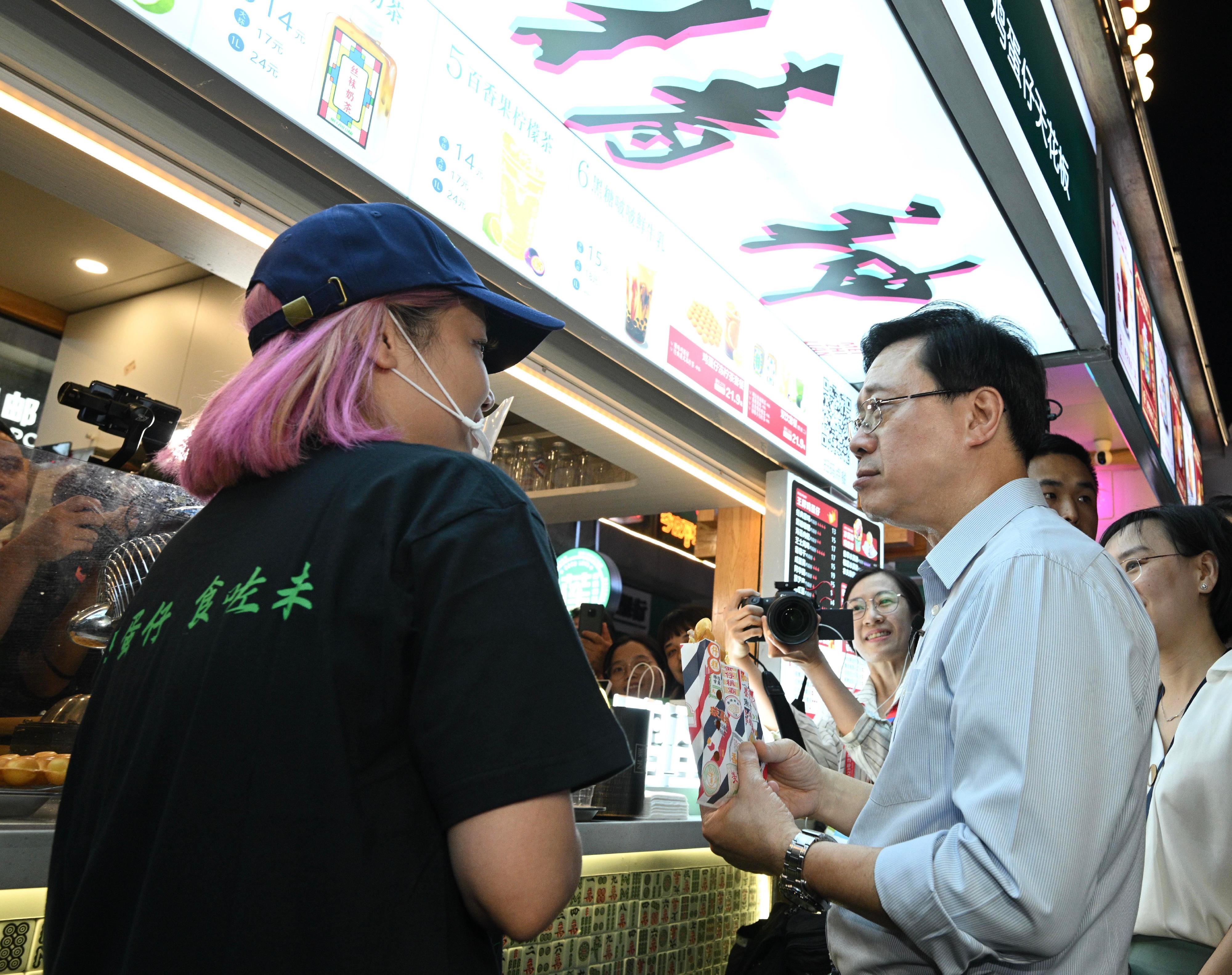 The Chief Executive, Mr John Lee, led a delegation to start his visit programme in Guiyang, today (July 6). Photo shows Mr Lee (right) tasting Hong Kong style food at the Qingyun Market.