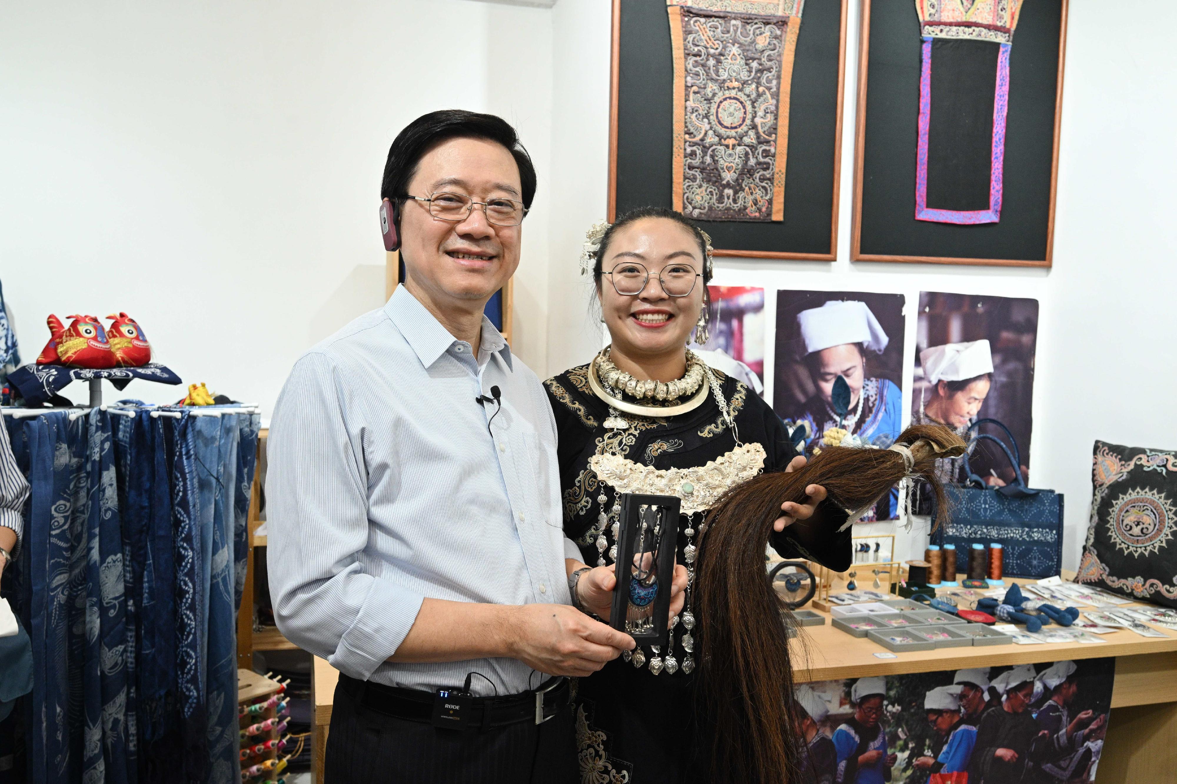 The Chief Executive, Mr John Lee, led a delegation to start his visit programme in Guiyang, today (July 6). Photo shows Mr Lee (left) listening to an introduction of the Guizhou Shuixian Horsetail Embroidery at the Qingyun Market.