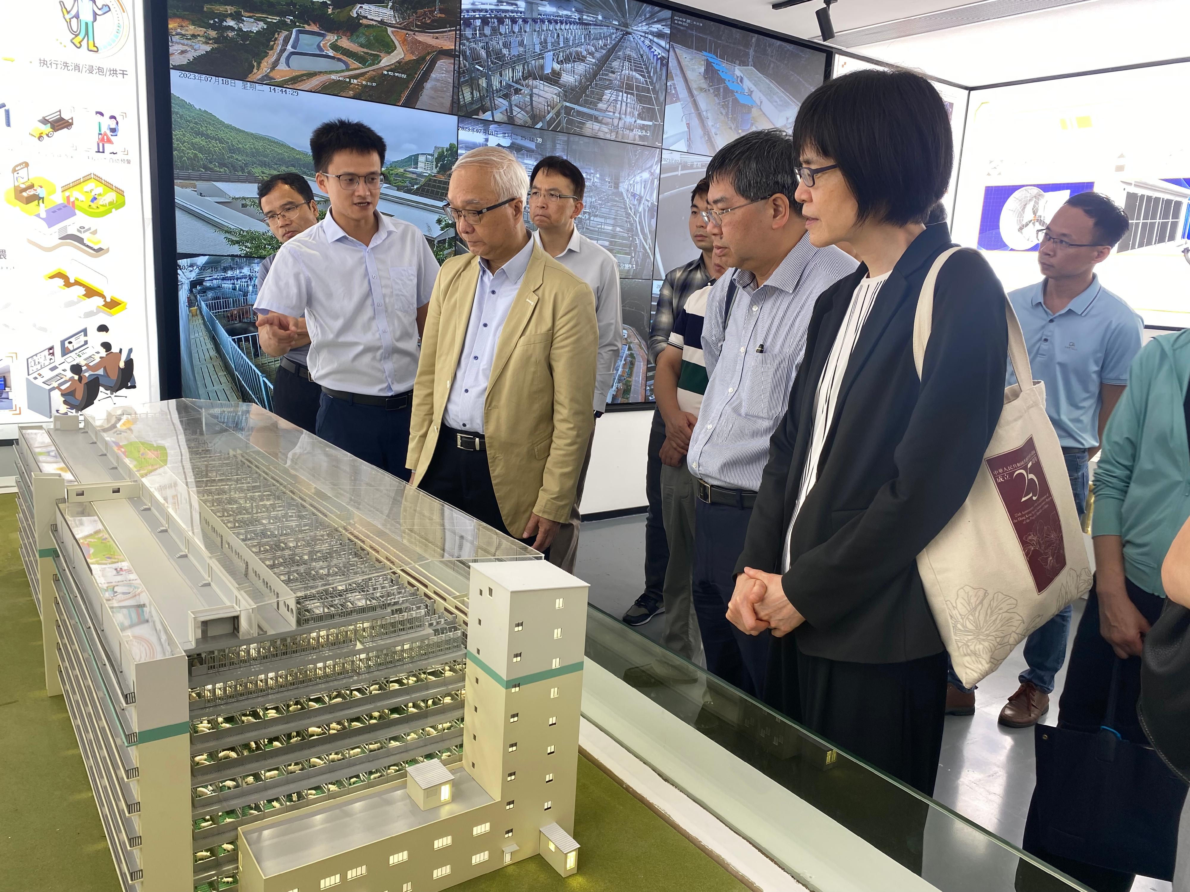The Secretary for Environment and Ecology, Mr Tse Chin-wan, began his visit in Guangzhou and Zhaoqing today (July 18) and visited a high-rise pig farm in Huadu District in Guangzhou in the afternoon. Photo shows Mr Tse (third right); the Permanent Secretary for Environment and Ecology (Food), Miss Vivian Lau (first right); and the Director of Agriculture, Fisheries and Conservation, Dr Leung Siu-fai (second right), receiving a briefing from a representative of the farm on technologies and operation of the multi-storey livestock farm facilities. 