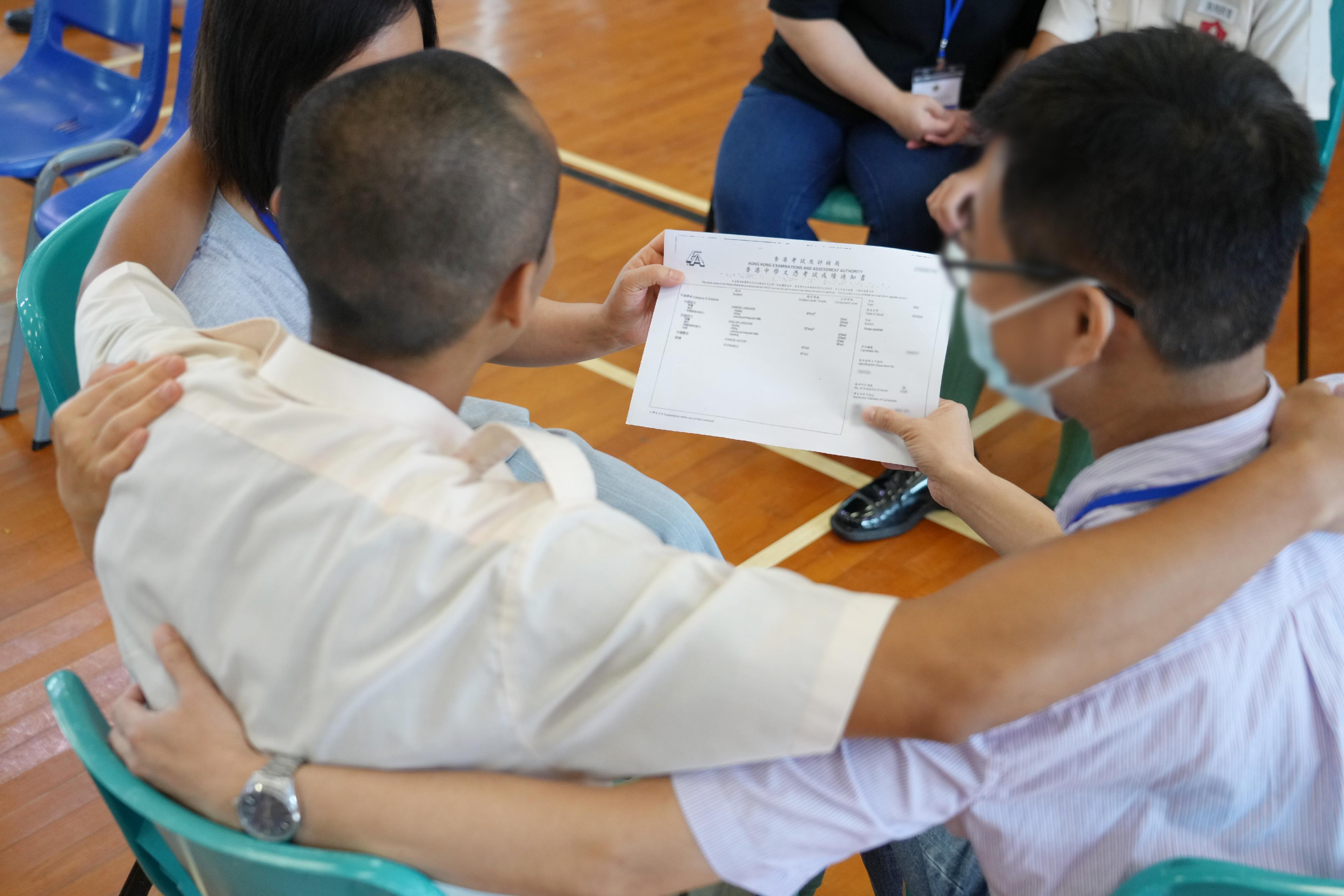 The results of the Hong Kong Diploma of Secondary Education (HKDSE) Examination were released today (July 19). Eighteen young persons in custody (PICs) enrolled in the HKDSE Examination this year. Photo shows a young PIC sharing his happiness at obtaining satisfactory HKDSE results with his family members.

