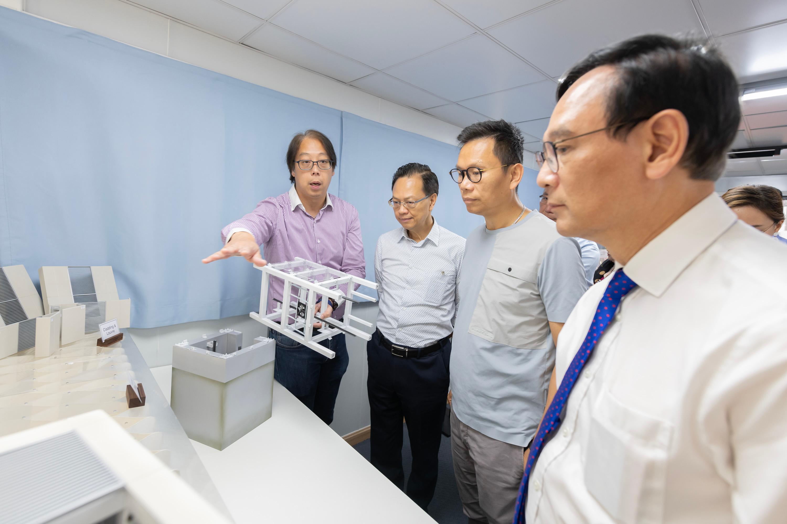 The Legislative Council (LegCo) Panel on Transport visited the Modular Integrated Construction (MiC) lift assembly yard under the Universal Accessibility Programme today (July 21) to learn about the Government's latest progress in building barrier-free facilities in public walkways. Photo shows the Chairman of the Panel on Transport, Mr Chan Han-pan (second right), and other LegCo Members observing the structure of a MiC lift through 3D-printed models.
