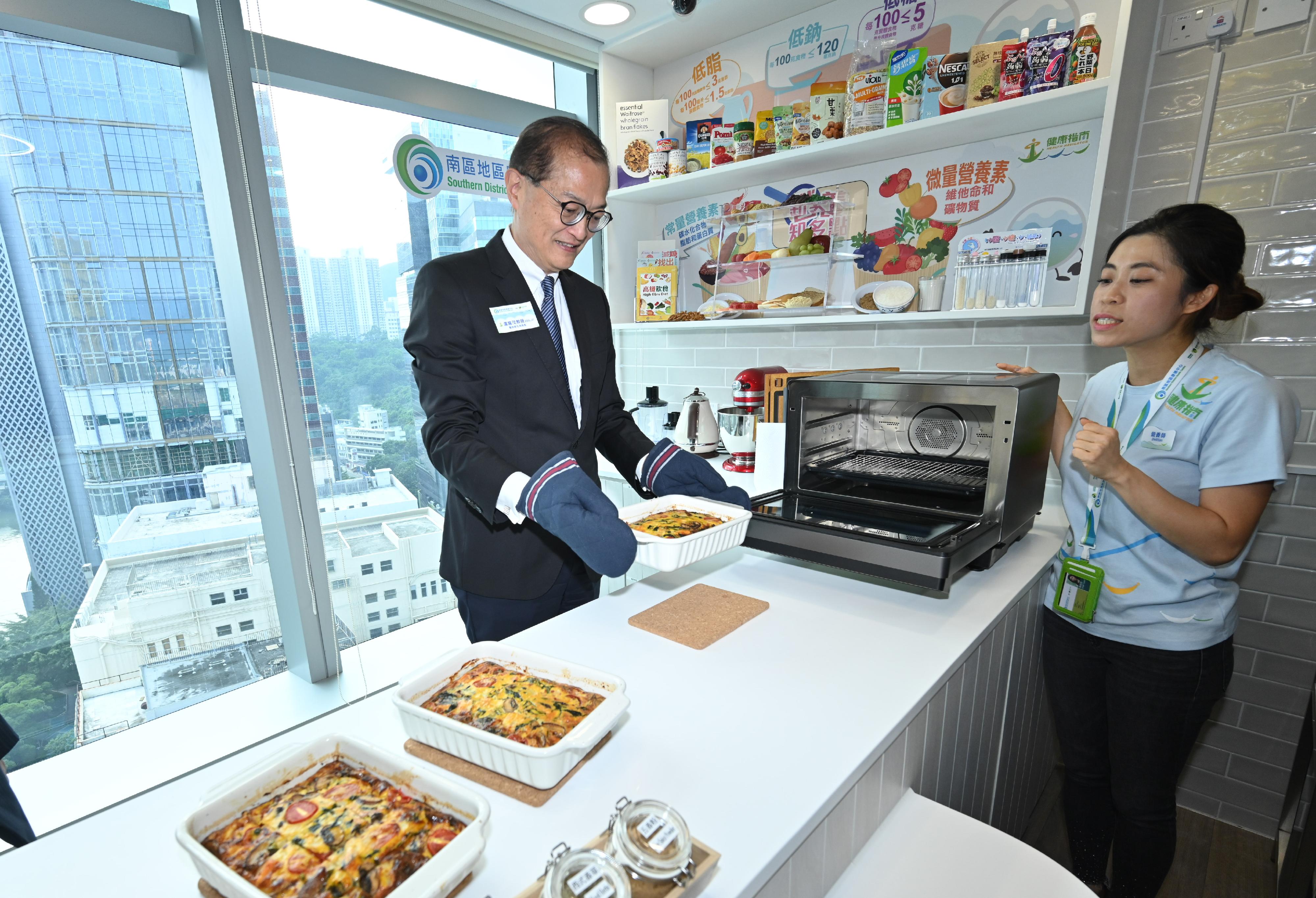 The Secretary for Health, Professor Lo Chung-mau (left), appreciates the dietitian teaching District Health Centre members to make healthy snacks during his tour in the Southern District Health Centre's dietetic counselling room this afternoon (July 26).