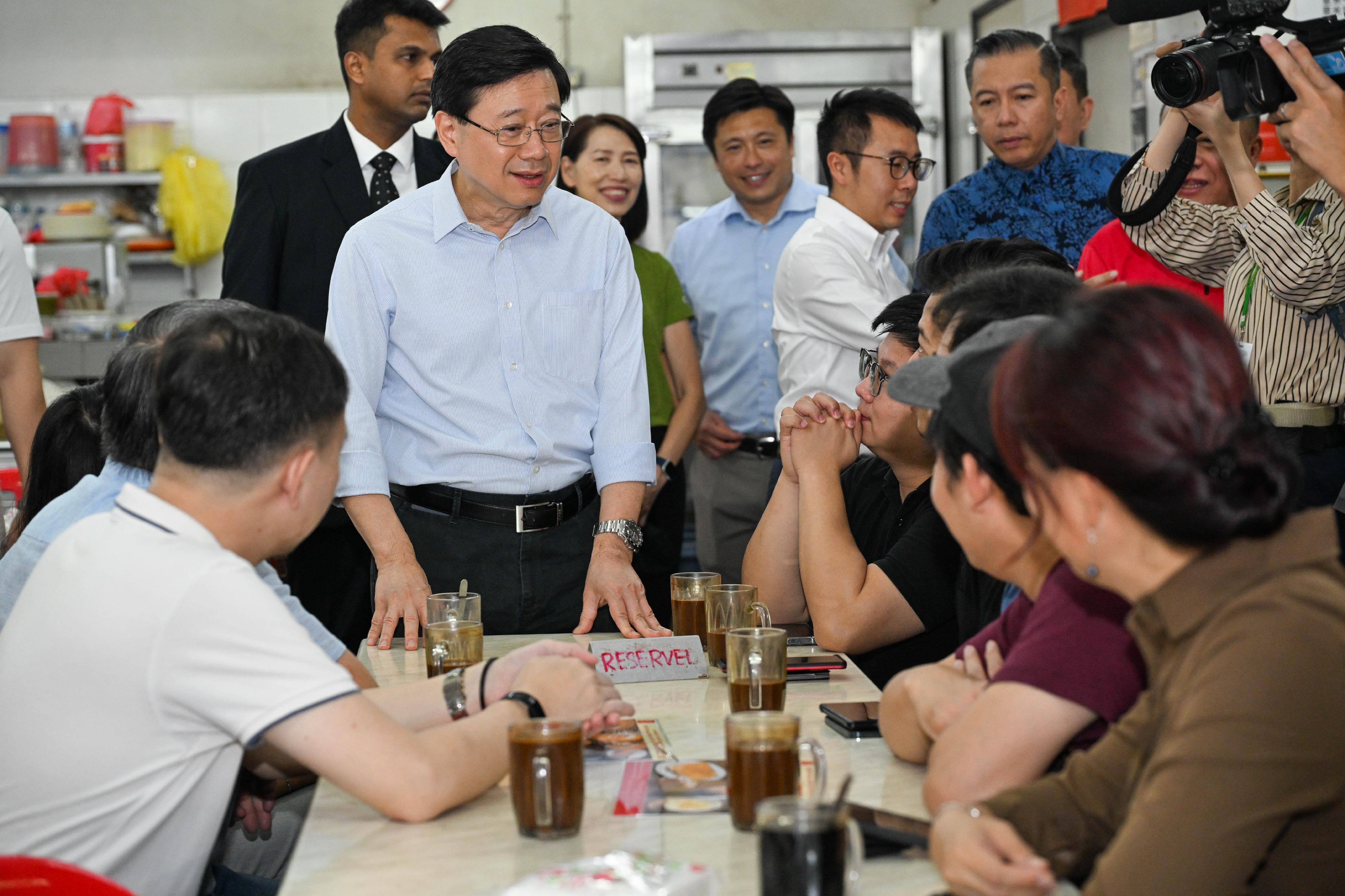 行政長官李家超今日（七月二十八日）在馬來西亞吉隆坡熟食中心享用地道早餐。圖示李家超與當地市民互動。