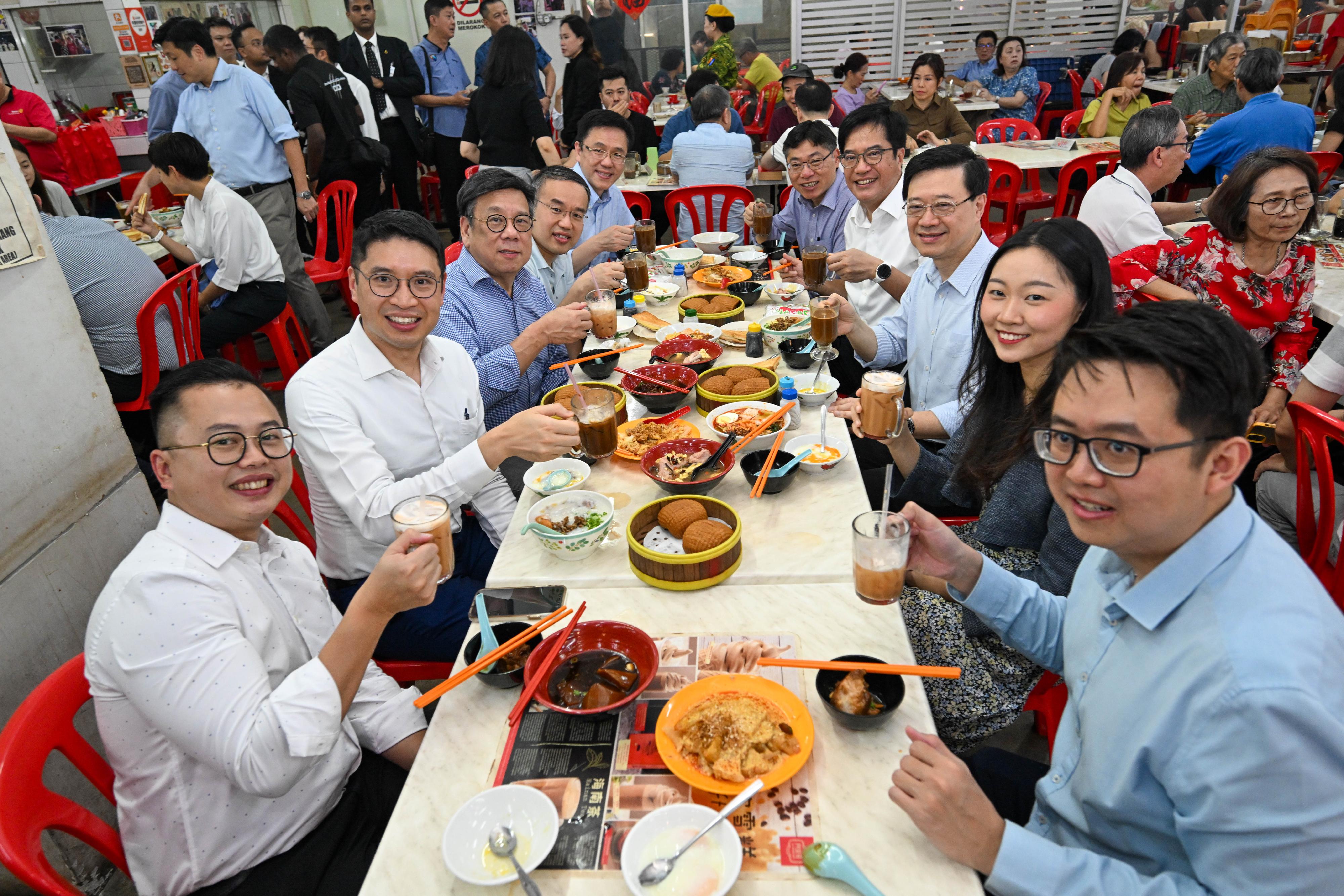 The Chief Executive, Mr John Lee, enjoyed a local breakfast at a hawker centre in Kuala Lumpur, Malaysia today (July 28). Photo shows Mr Lee (third right); the Deputy Financial Secretary, Mr Michael Wong (fourth right); the Secretary for Financial Services and the Treasury, Mr Christopher Hui (fourth left); the Secretary for Commerce and Economic Development, Mr Algernon Yau (third left); the Secretary for Transport and Logistics, Mr Lam Sai-hung (fifth right); and the Secretary for Innovation, Technology and Industry, Professor Sun Dong (fifth left), and colleagues of the Hong Kong Economic and Trade Office in Jakarta, enjoying a local breakfast. 