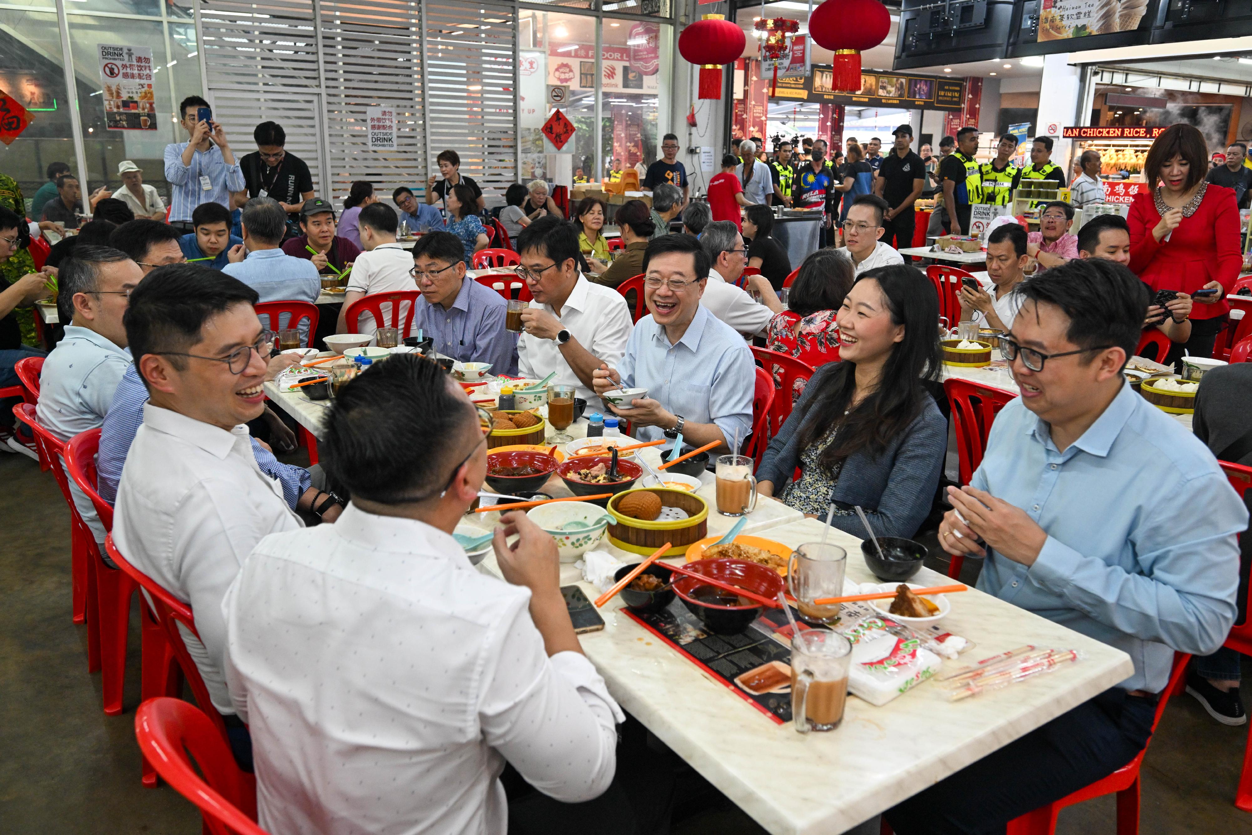The Chief Executive, Mr John Lee (third right), enjoys a local breakfast at a hawker centre in Kuala Lumpur, Malaysia today (July 28).