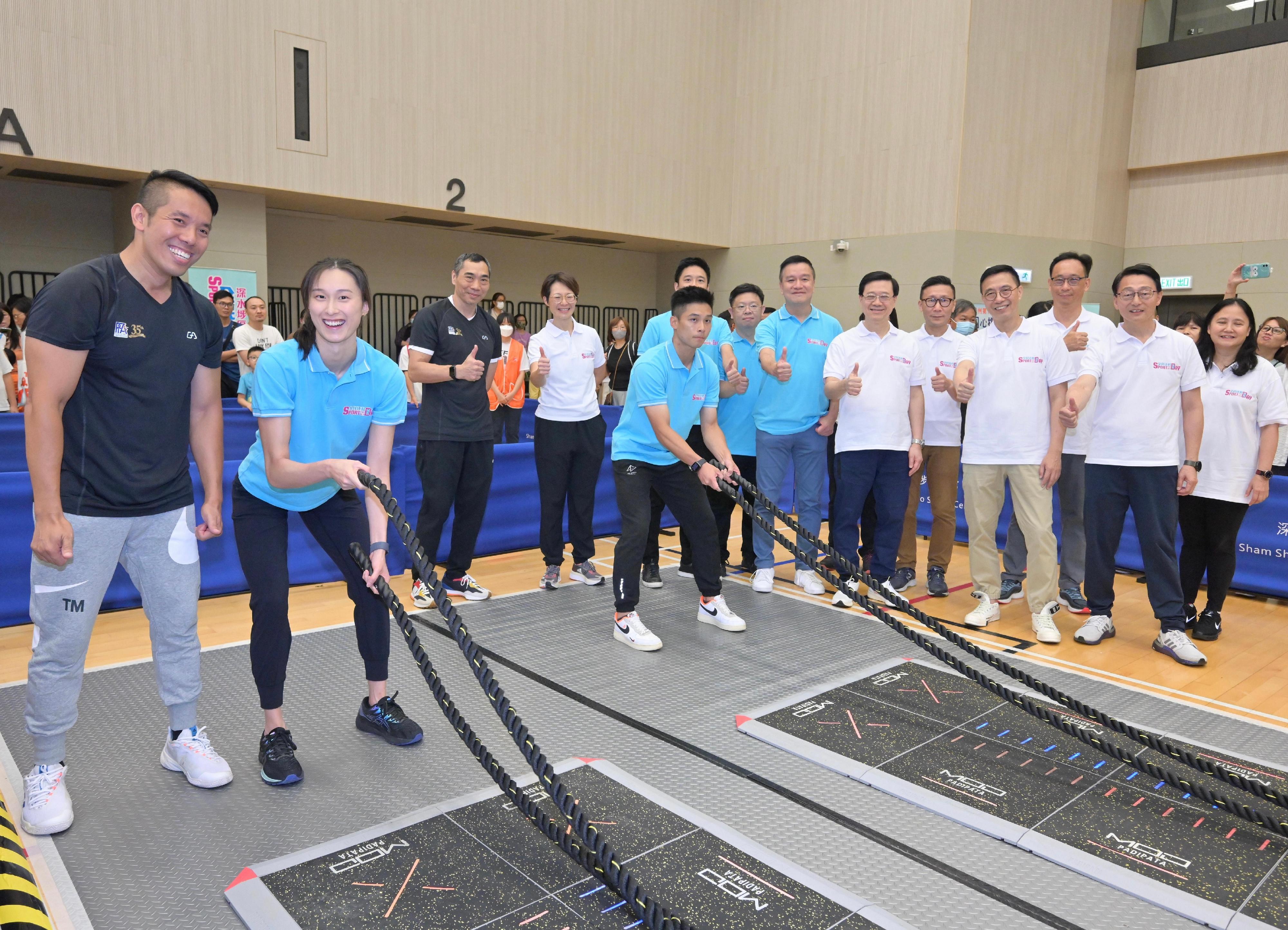 The Chief Executive, Mr John Lee, attended the Sport For All Day 2023 held by the Leisure and Cultural Services Department at the Sham Shui Po Sports Centre and took part in sports fun games this afternoon (August 6). Photo shows Mr Lee (sixth right) watching swimming athlete Tam Hoi-lam (second left) and wushu athlete Lau Tsz-hong (fifth left) in electronic battling rope play-in session.
