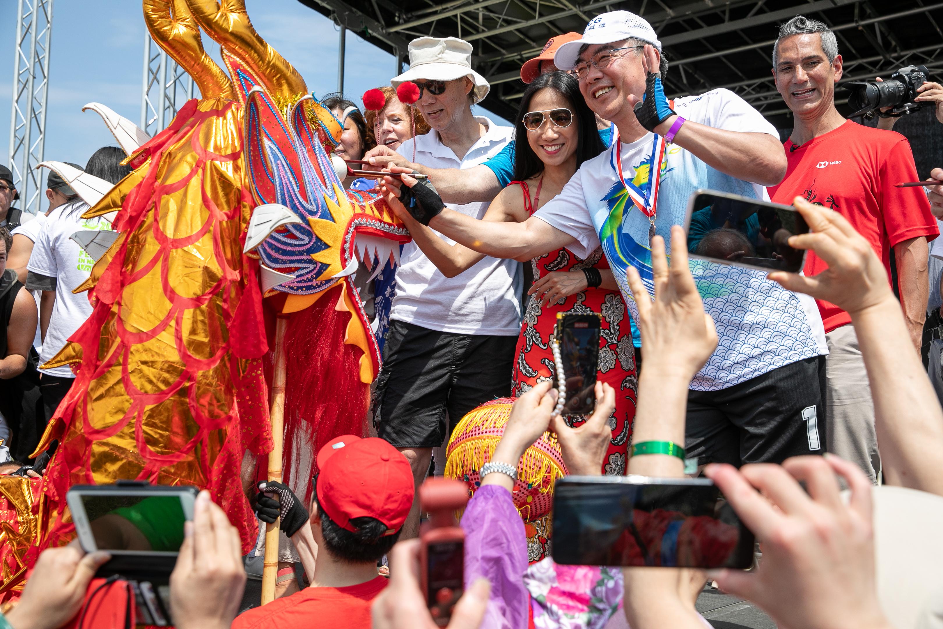The 31st edition of the Hong Kong Dragon Boat Festival in New York was held at the Flushing Meadows Corona Park on August 12 and 13 (New York time). Photo shows the Director of the Hong Kong Economic and Trade Office in New York, Ms Candy Nip (third right); the Chairman of the Hong Kong Dragon Boat Festival in New York Inc., Mr Henry Wan (fourth right), and other guests take part in the eye-dotting ceremony at the opening ceremony of the Hong Kong Dragon Boat Festival in New York on August 12 (New York time).