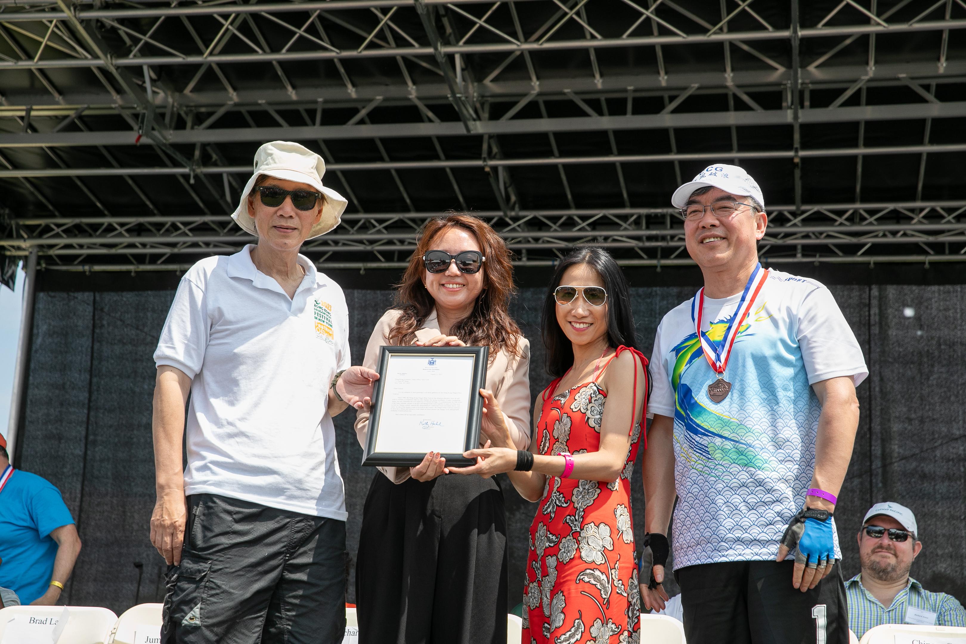 The 31st edition of the Hong Kong Dragon Boat Festival in New York was held at the Flushing Meadows Corona Park on August 12 and 13 (New York time). Photo shows the Director of Asian Affairs of New York State Governor's Executive Chamber, Ms Elaine Fan (second left), presents a proclamation on behalf of the Governor of New York State, Ms Kathy Hochul, to the Director of Hong Kong Economic and Trade Office in New York, Ms Candy Nip (second right). Also pictured are the Chairman of the Hong Kong Dragon Boat Festival in New York Inc., Mr Henry Wan (first left), and the Consul General of the People's Republic of China in New York, Mr Huang Ping (first right).