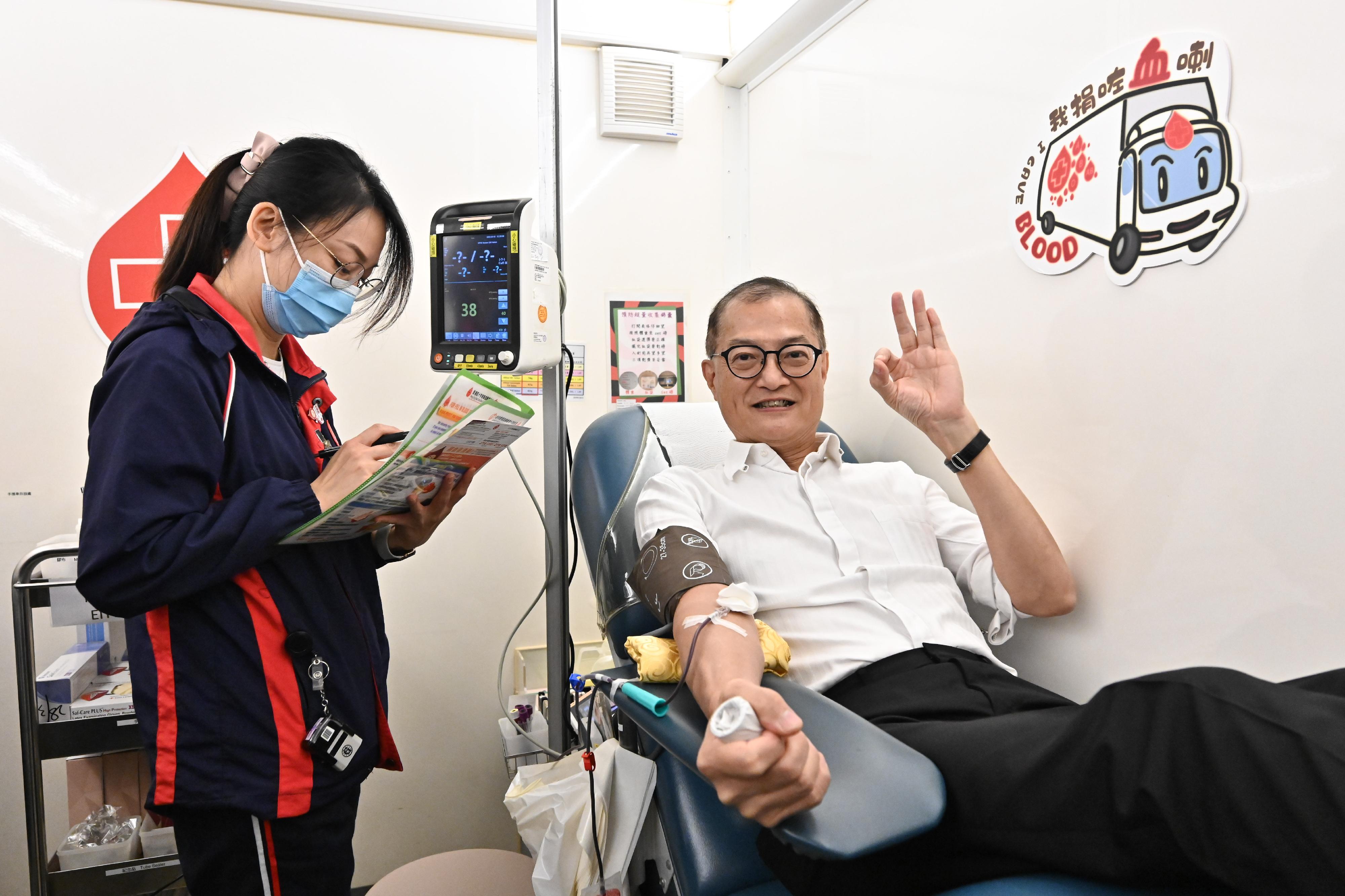 The Secretary for Health, Professor Lo Chung-mau (right), donates blood on the mobile blood donation vehicle of the Hong Kong Red Cross Blood Transfusion Service parked at the Central Government Offices today (August 14) to do his bit to rescue patients in need.